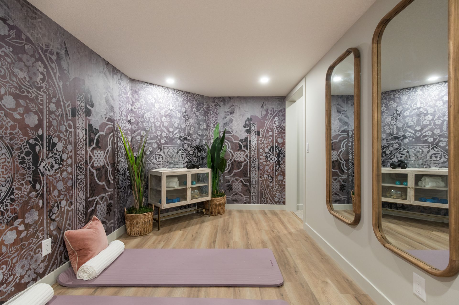 A room with a yoga mat and two mirrors on the wall.