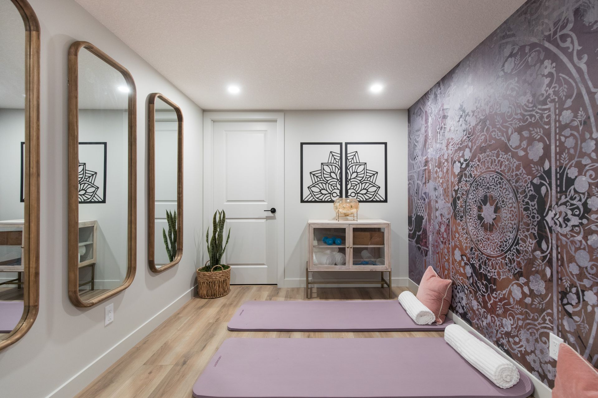 A room with two yoga mats , mirrors and a purple wall.