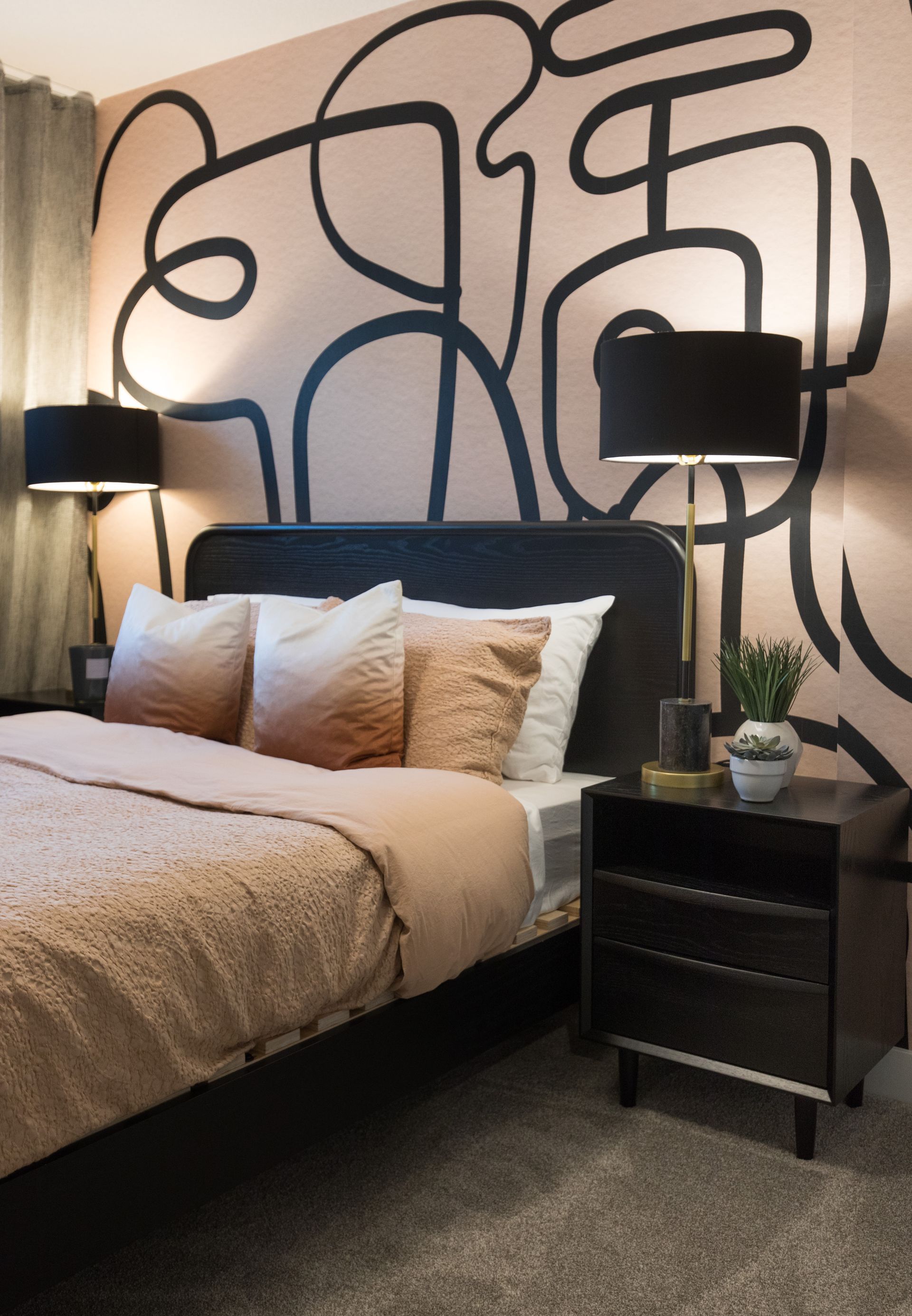 A bedroom with a bed , nightstand and lamps