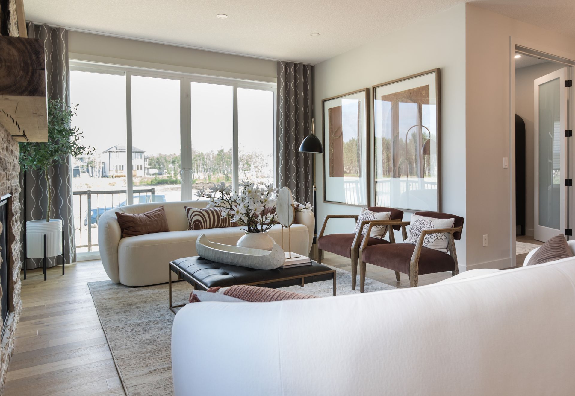 A living room with a white couch , chairs , coffee table and large windows.