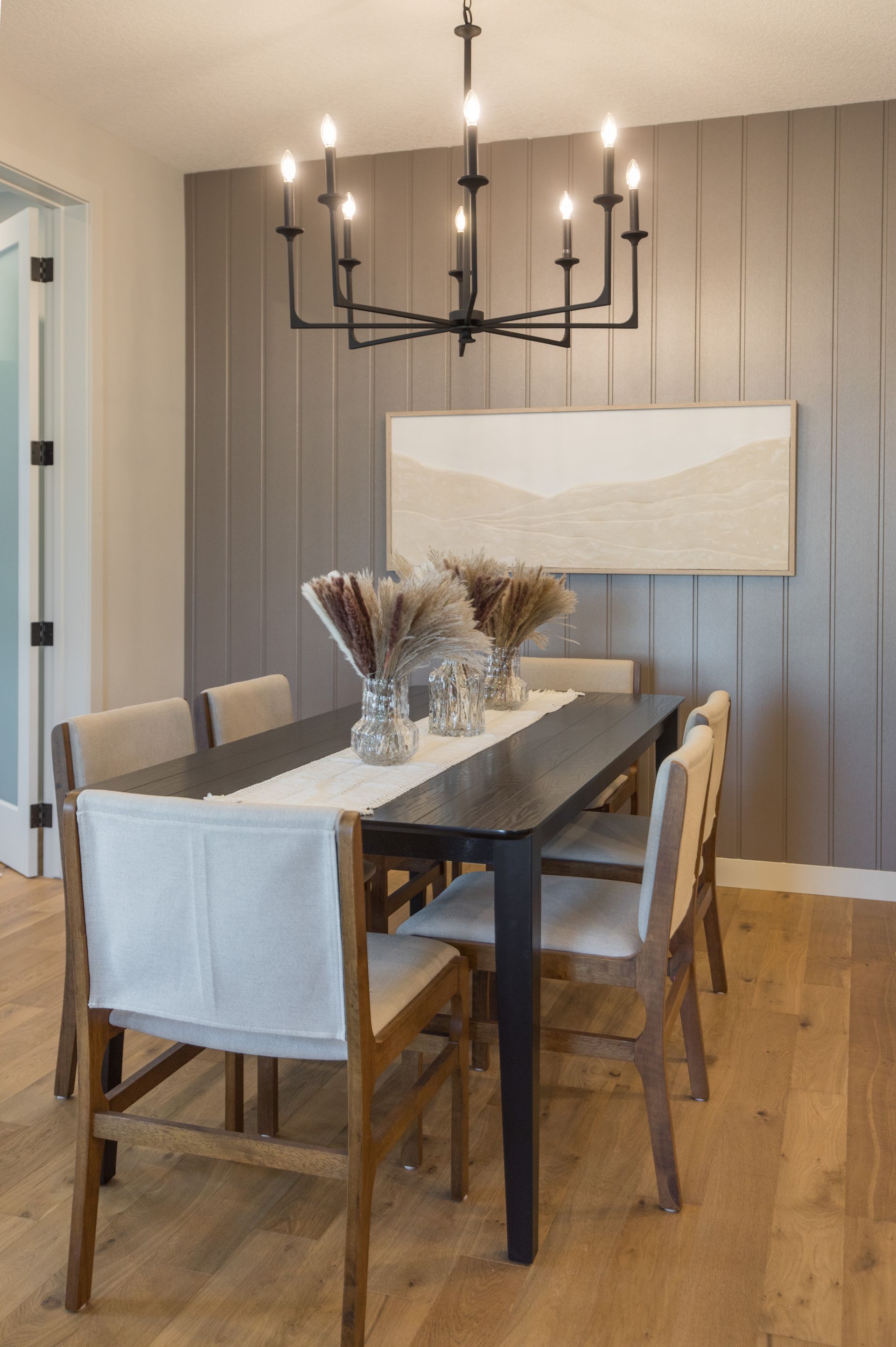 A dining room with a table and chairs and a chandelier hanging from the ceiling.