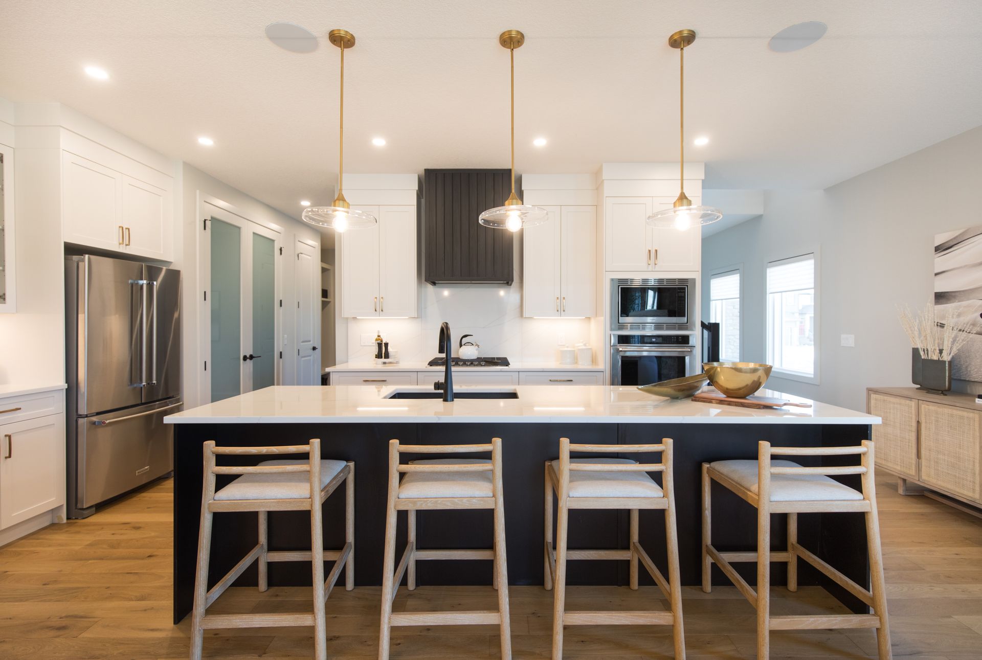 A kitchen with a large island , stools and a refrigerator.