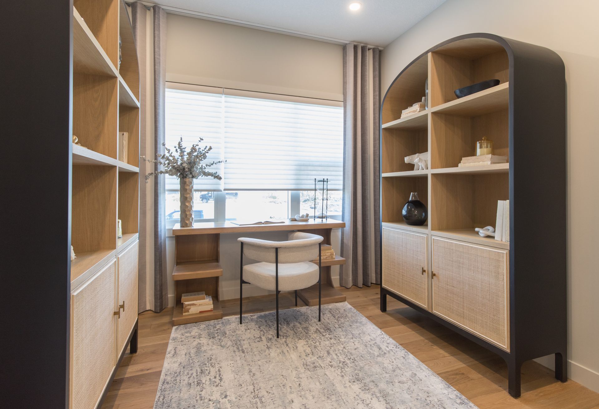 A home office with a desk , chair , bookshelf and rug.