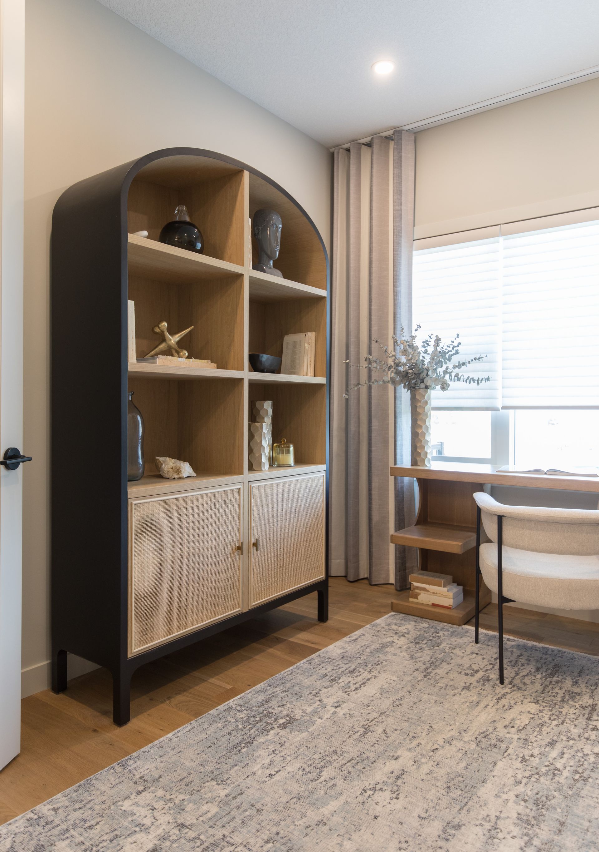A room with a bookshelf , chair , desk and window.