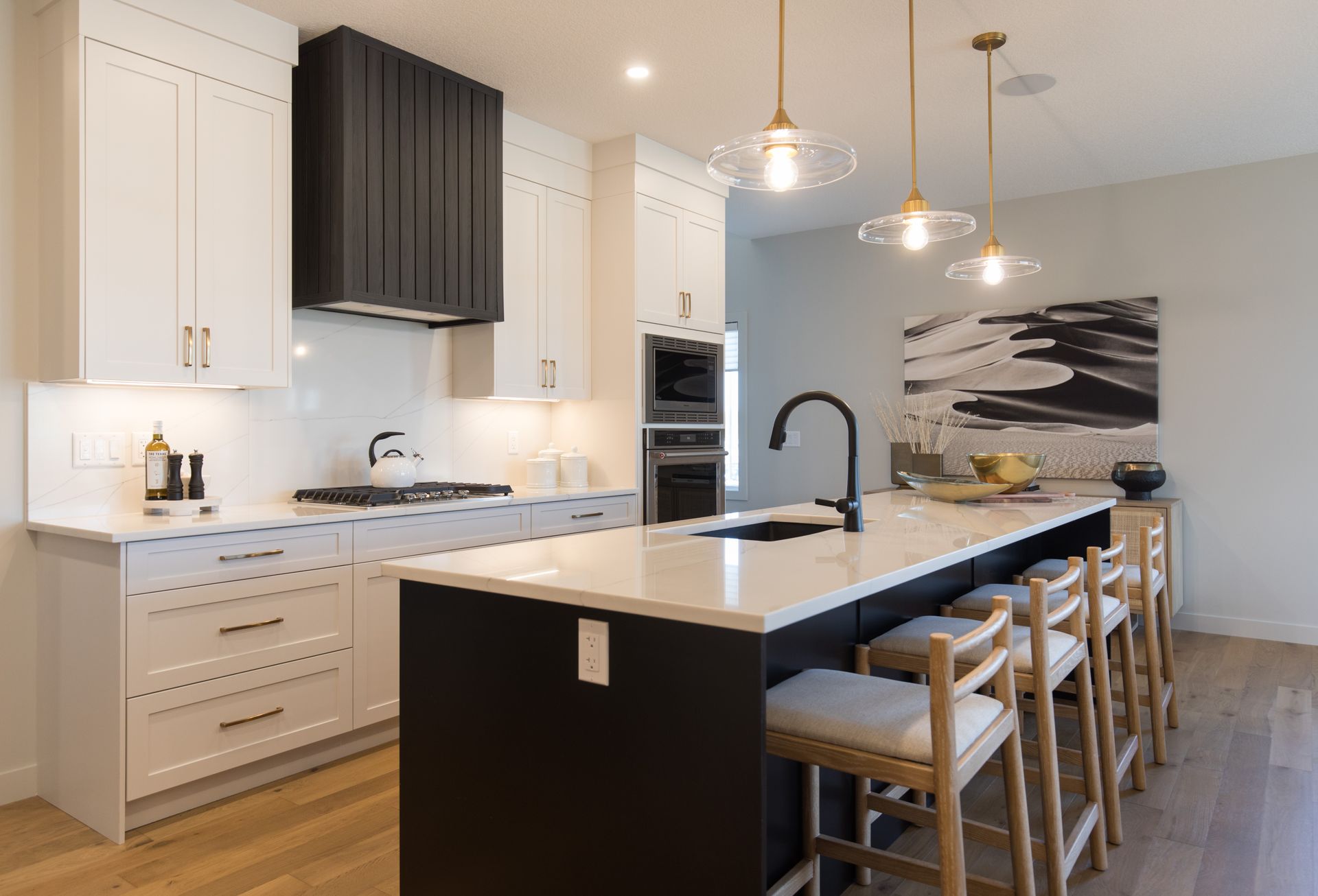 A kitchen with black and white cabinets , a large island , and stools.