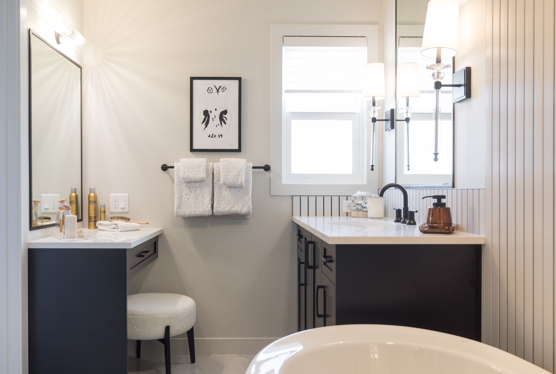 A bathroom with a tub , sink , mirror and vanity.