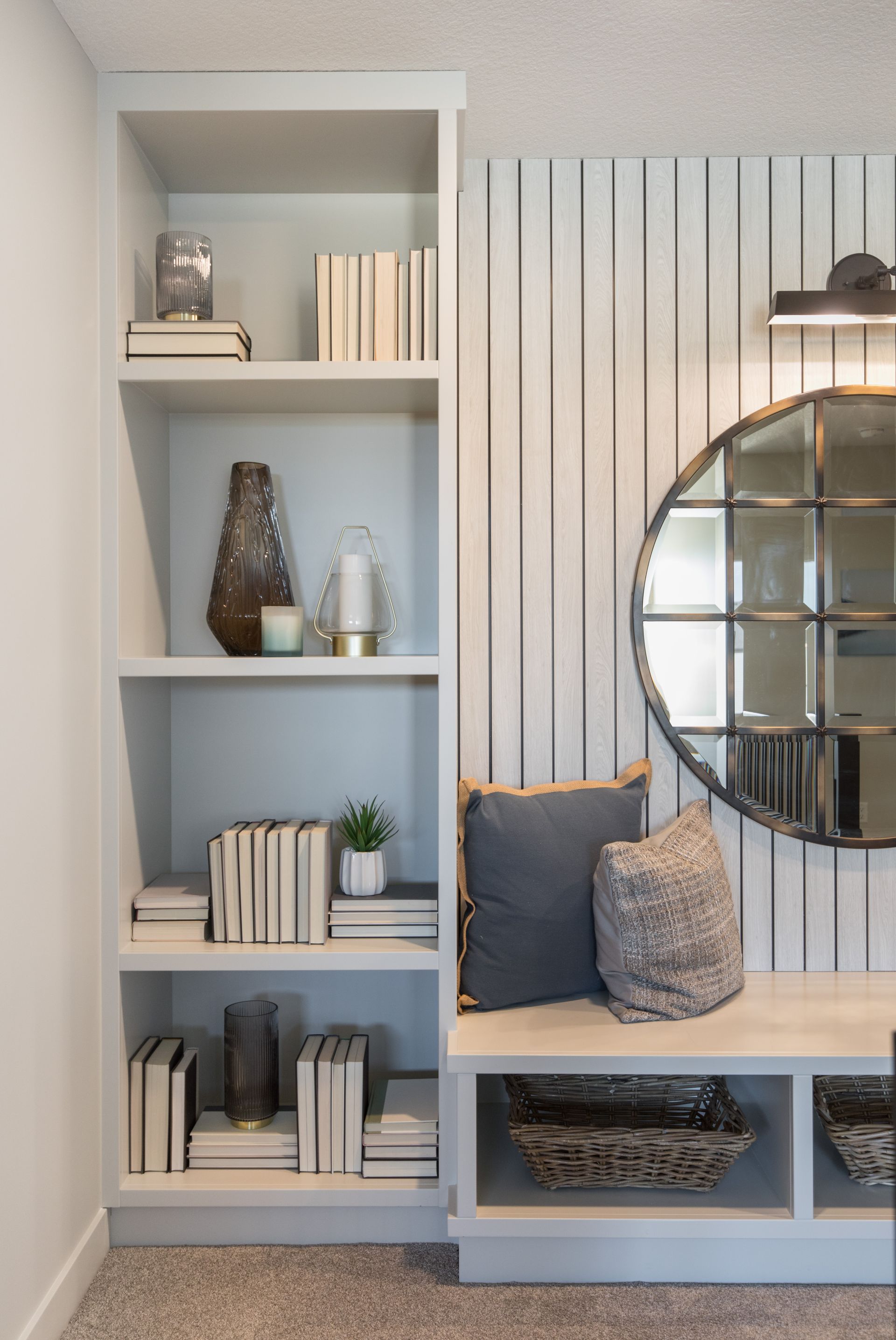 A living room with a bench , shelves , and a mirror.
