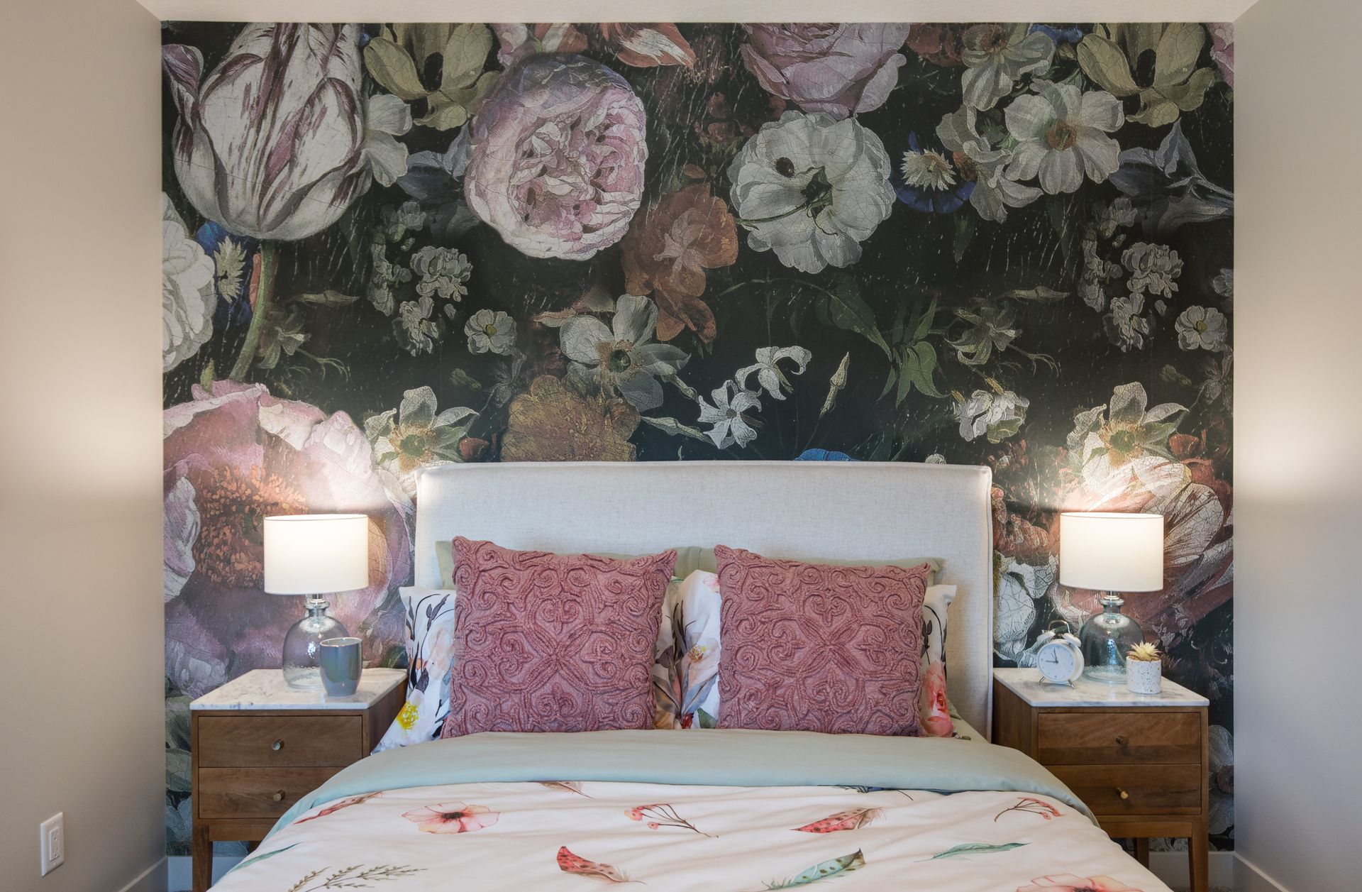 A bedroom with a bed , nightstands , and a floral wallpaper on the wall.