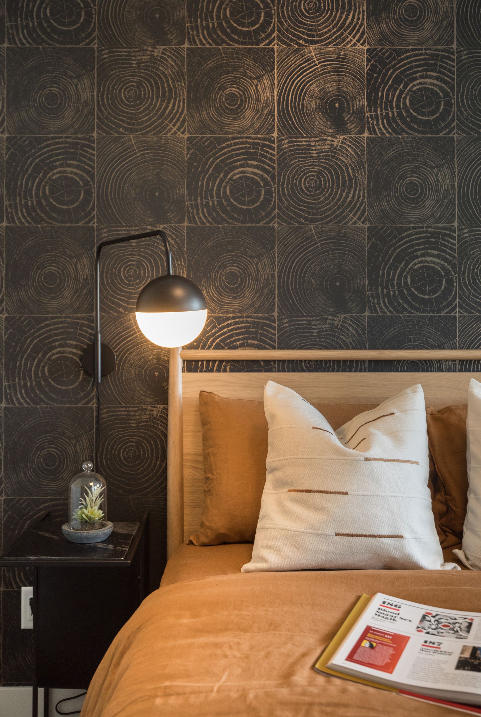 A bedroom with a bed , nightstand , lamp and a book on the bed.