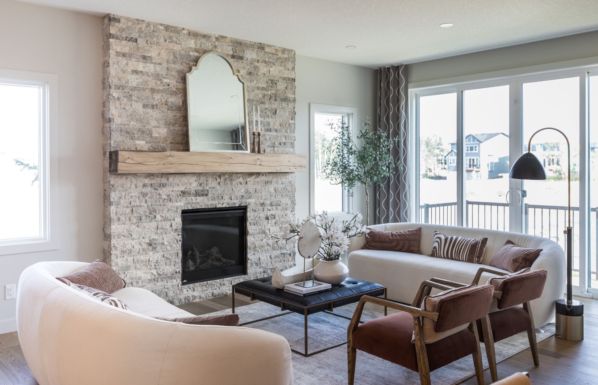 A living room with a fireplace , couch , chairs and a large window.