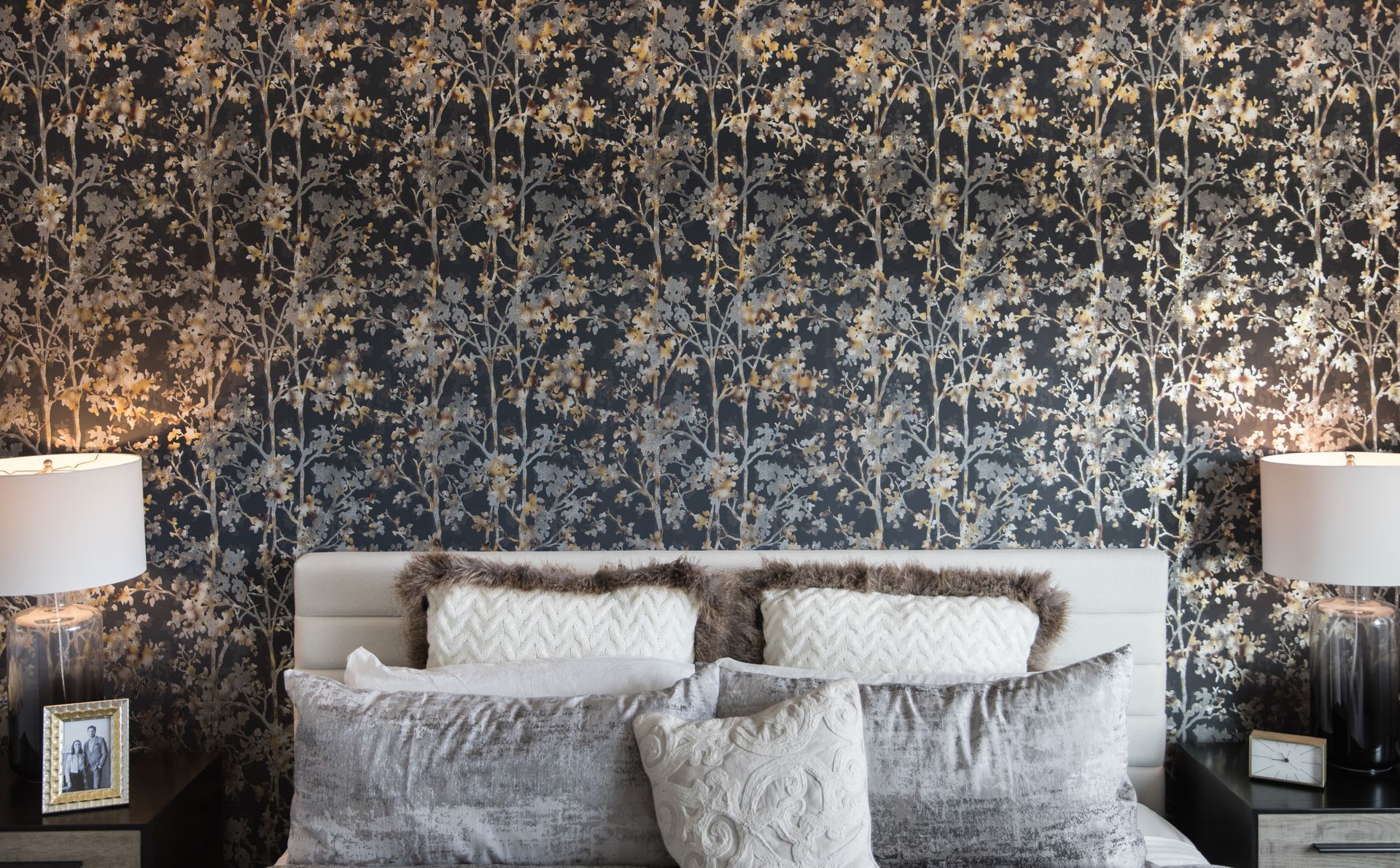 A bedroom with a bed , two lamps and a picture on the nightstand.