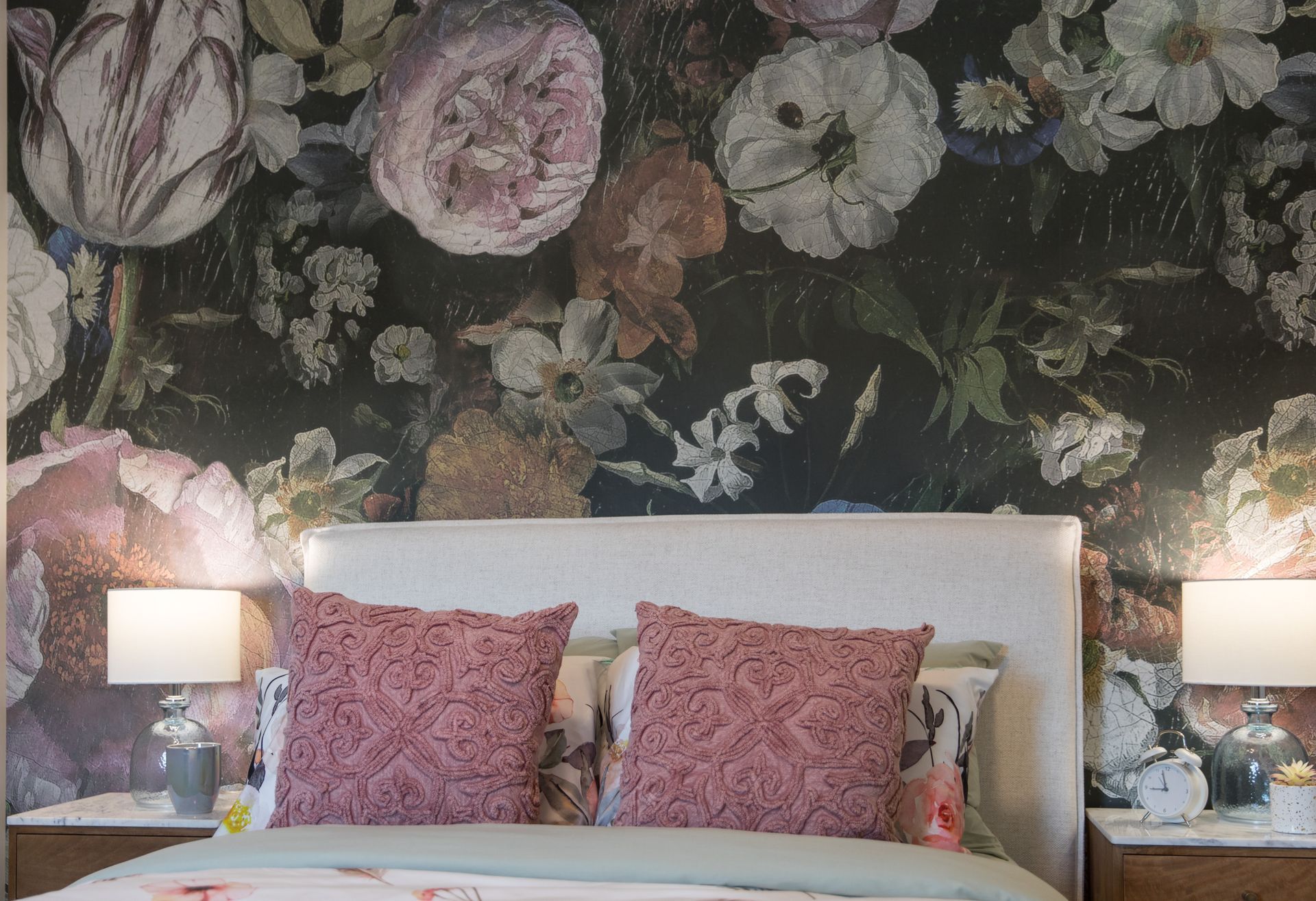 A bedroom with a large floral wallpaper on the wall