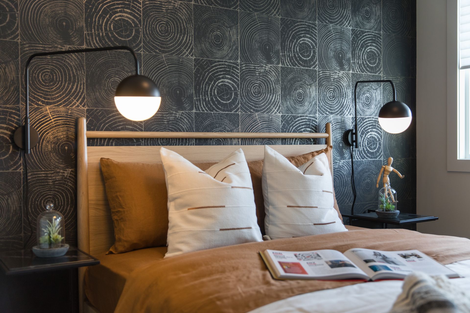 A bedroom with a bed , pillows , lamps and a book on the bed.