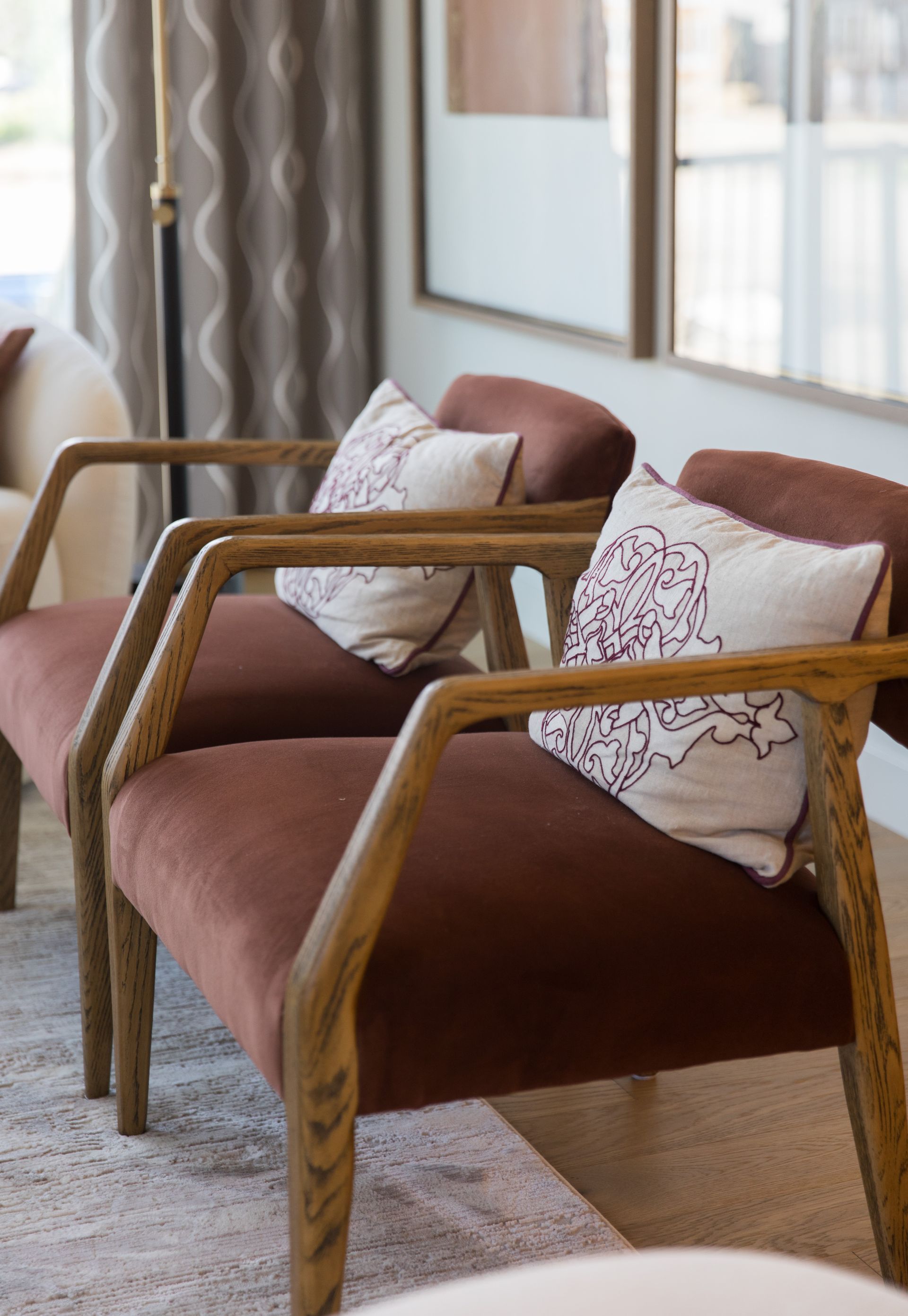 Two chairs with pillows on them are sitting next to each other in a living room.