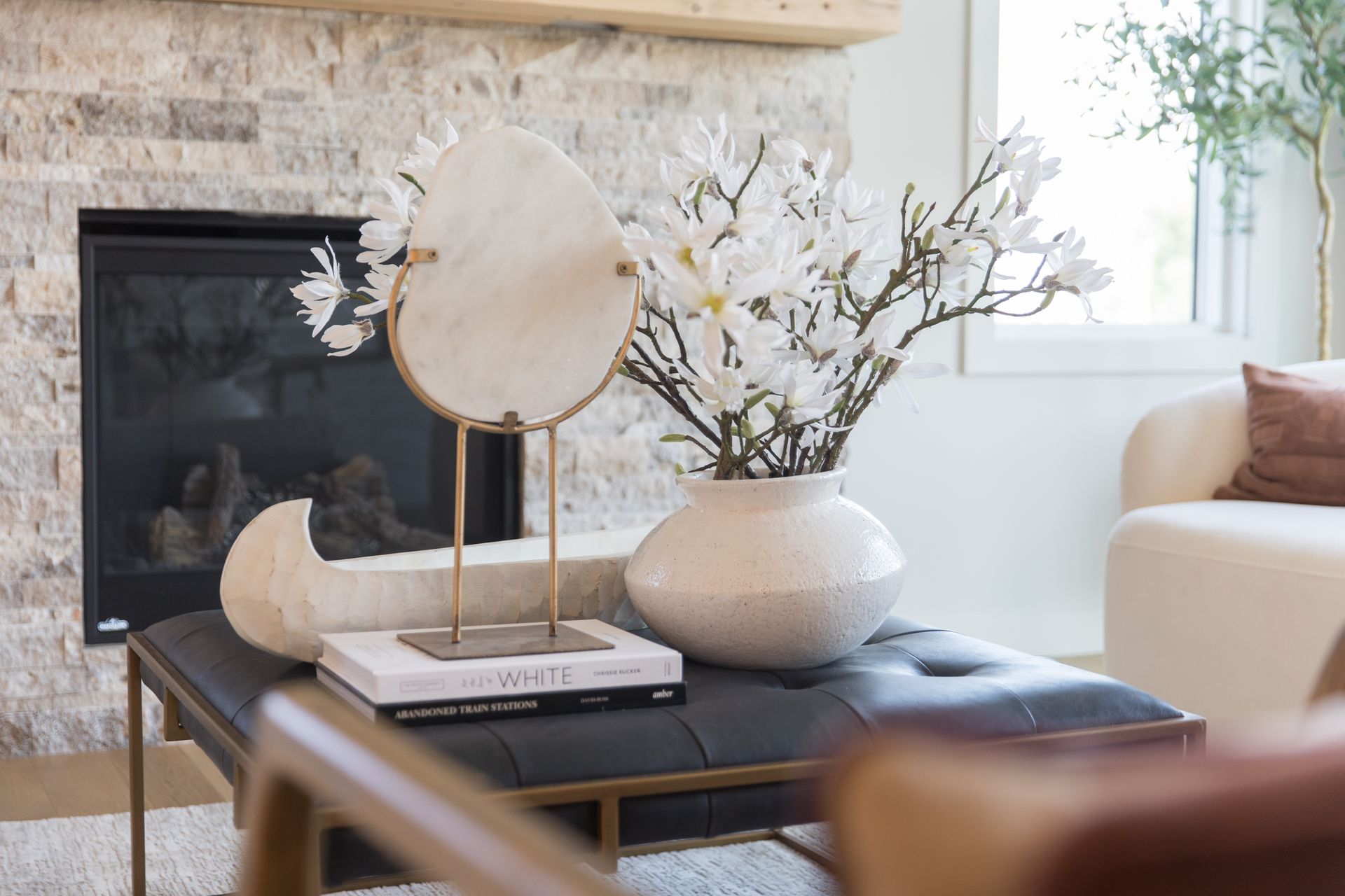 A living room with a fireplace and a coffee table with a vase of flowers on it.