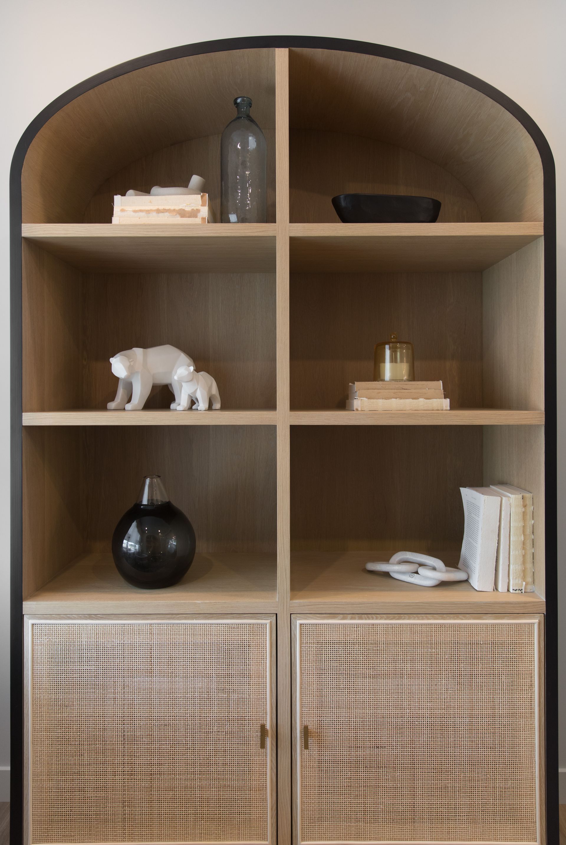 A wooden bookshelf with wicker doors and shelves in a living room.
