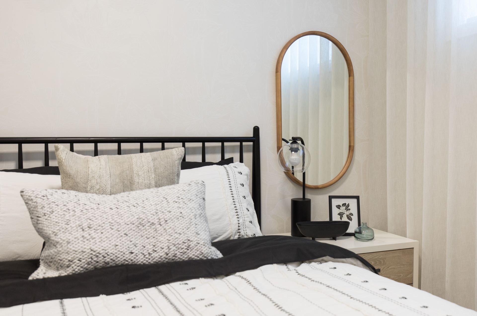 A bedroom with a bed , nightstand , and mirror.