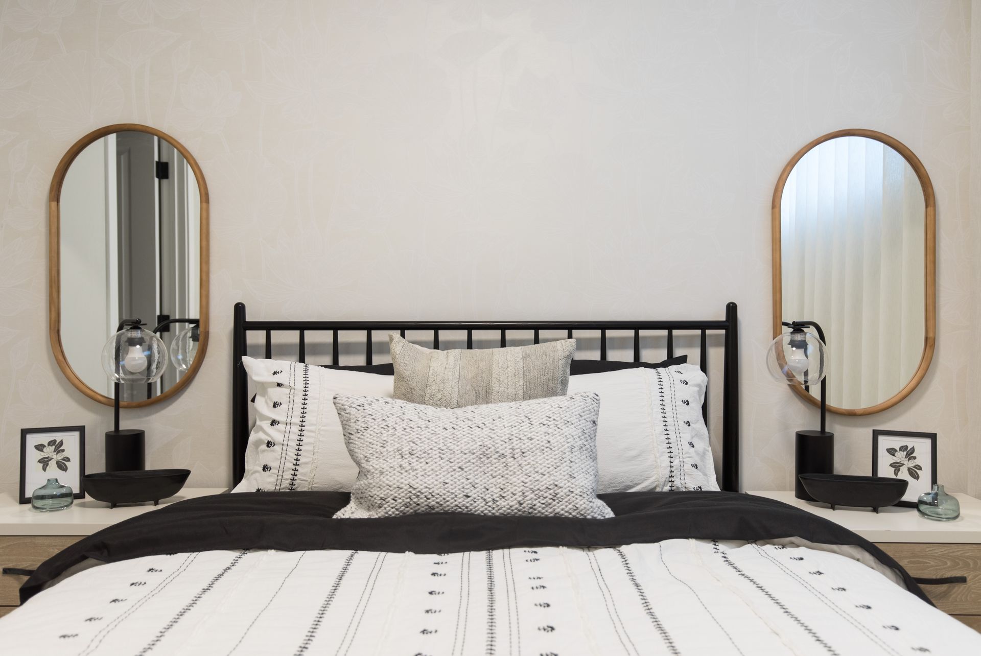 A bedroom with a bed , two mirrors and two nightstands.