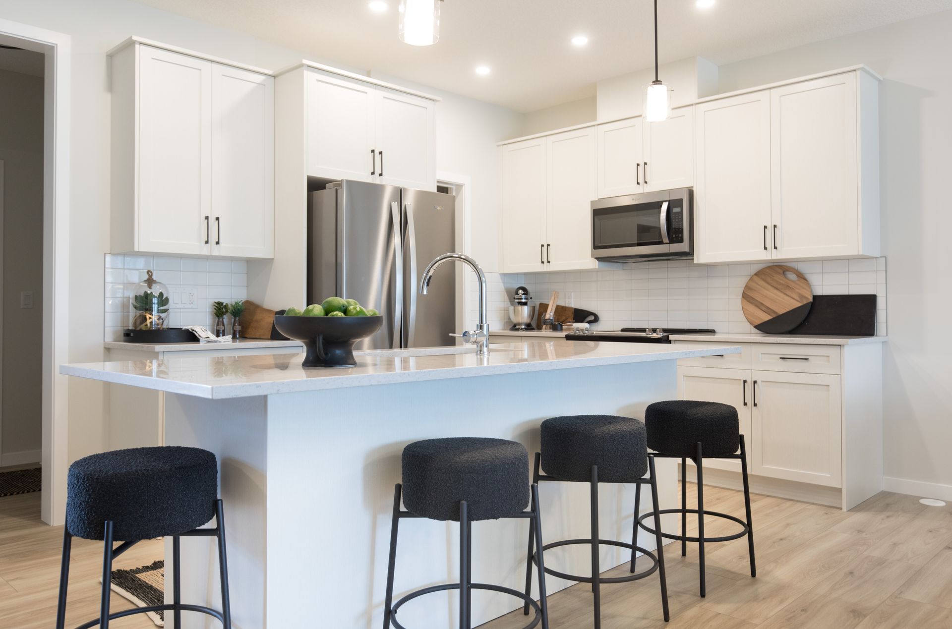 A kitchen with white cabinets and stools and a large island.