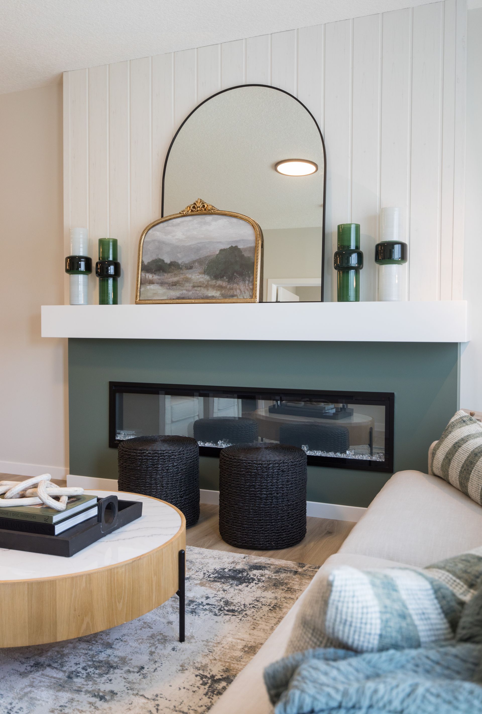 A living room with a fireplace , couch , coffee table and mirror.