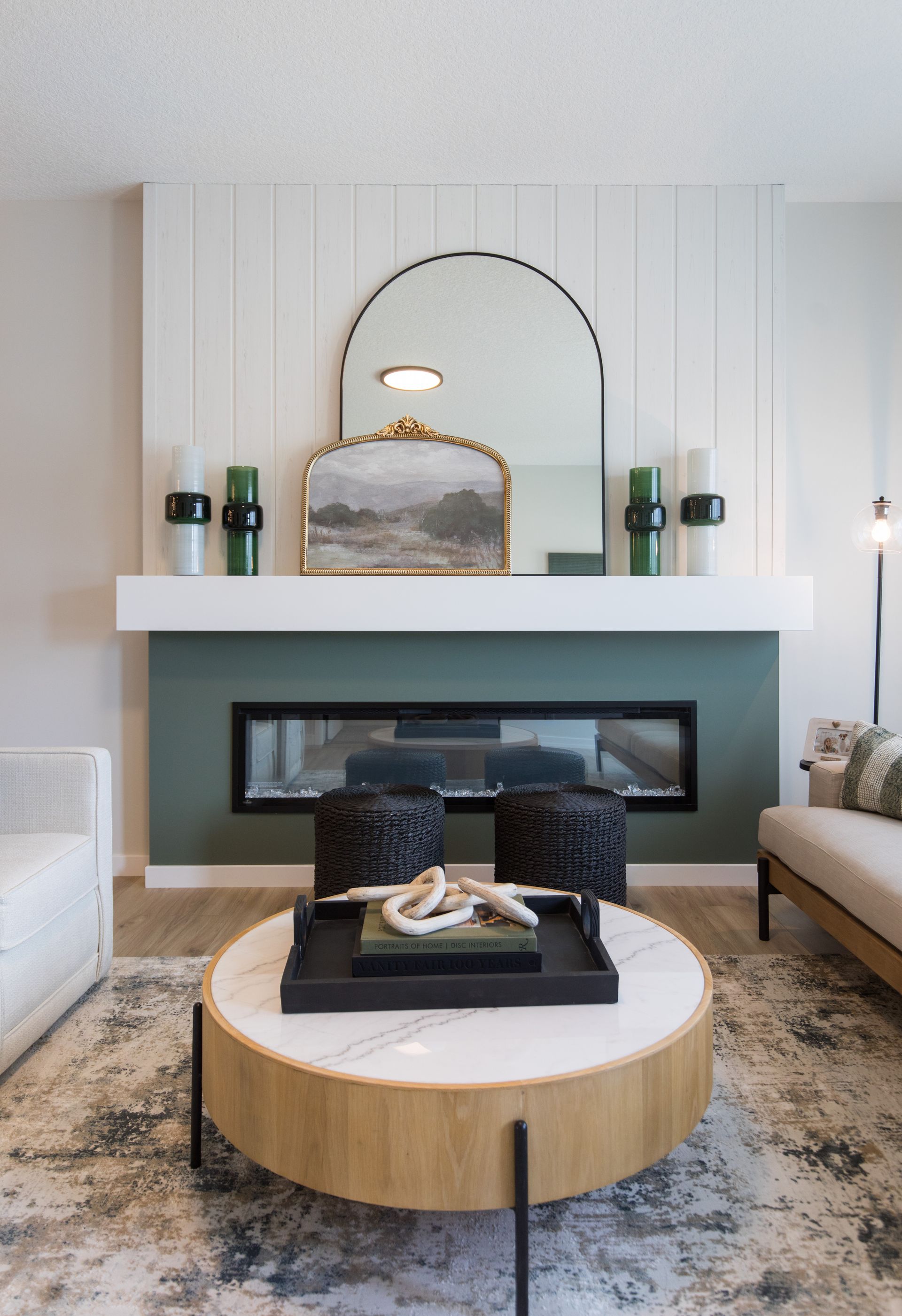 A living room with a fireplace , couch , coffee table and mirror.
