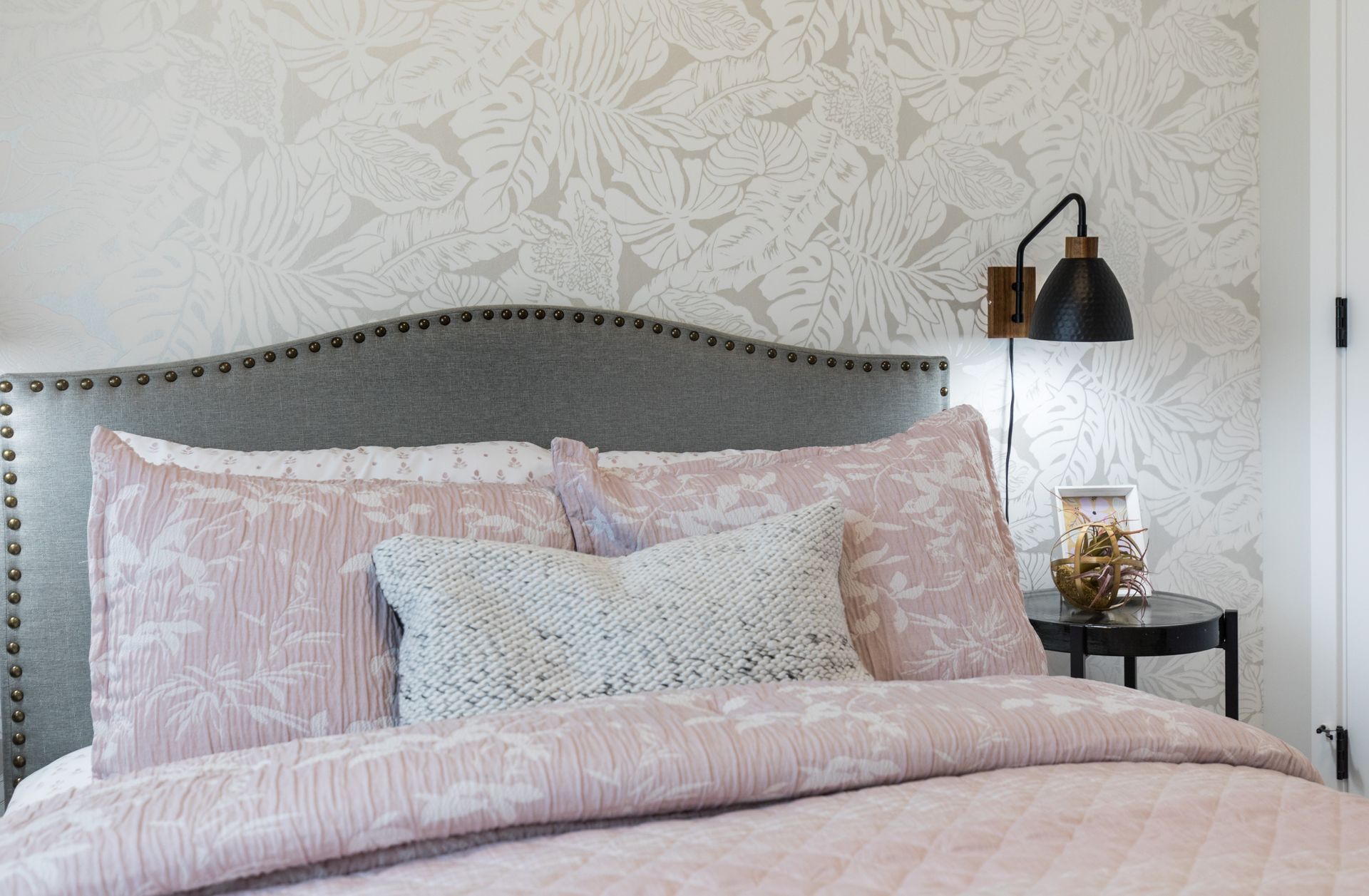 A bedroom with a bed , nightstand , and lamp.