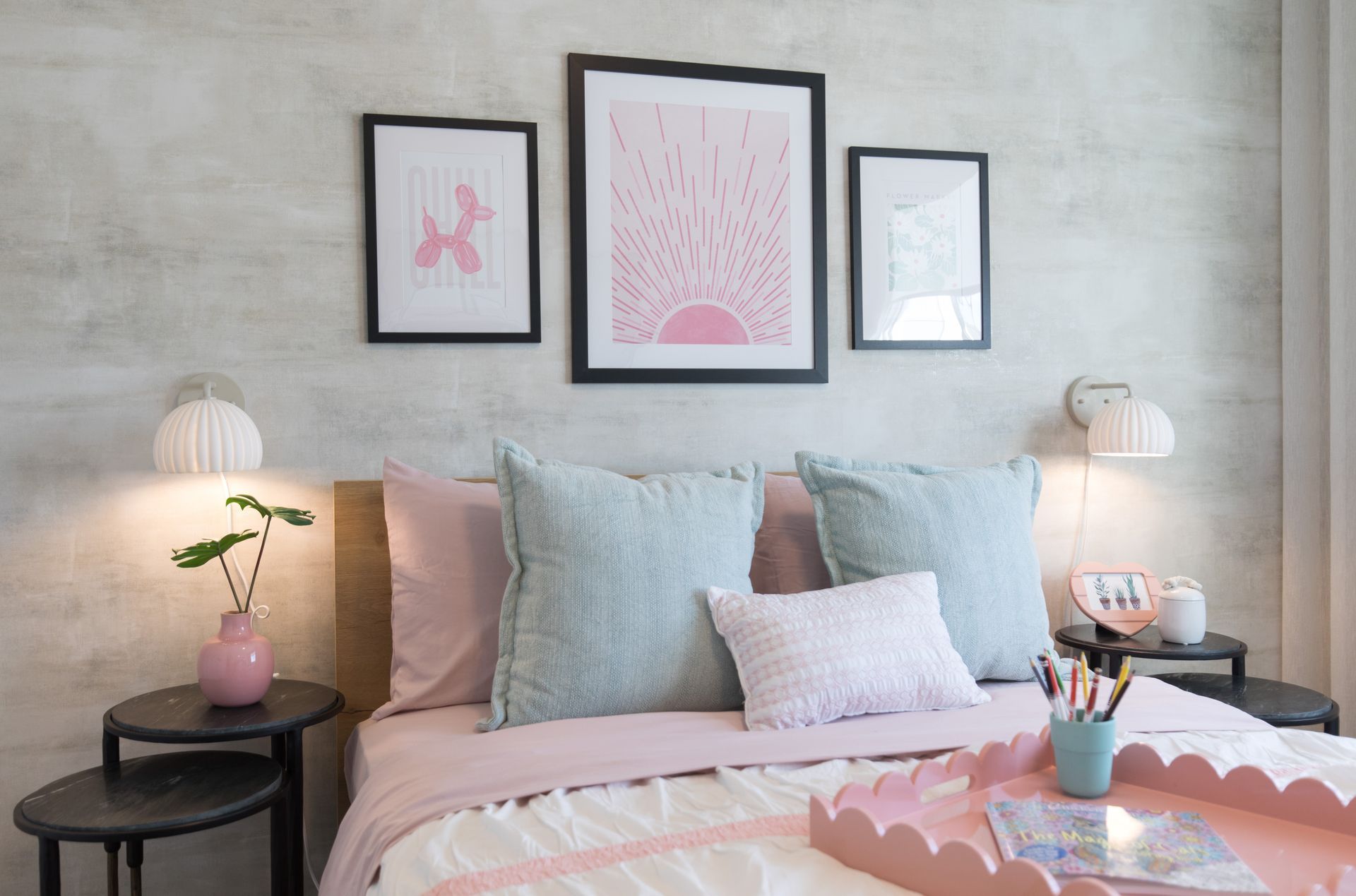 A bedroom with a bed , tables , lamps and a tray on the bed.