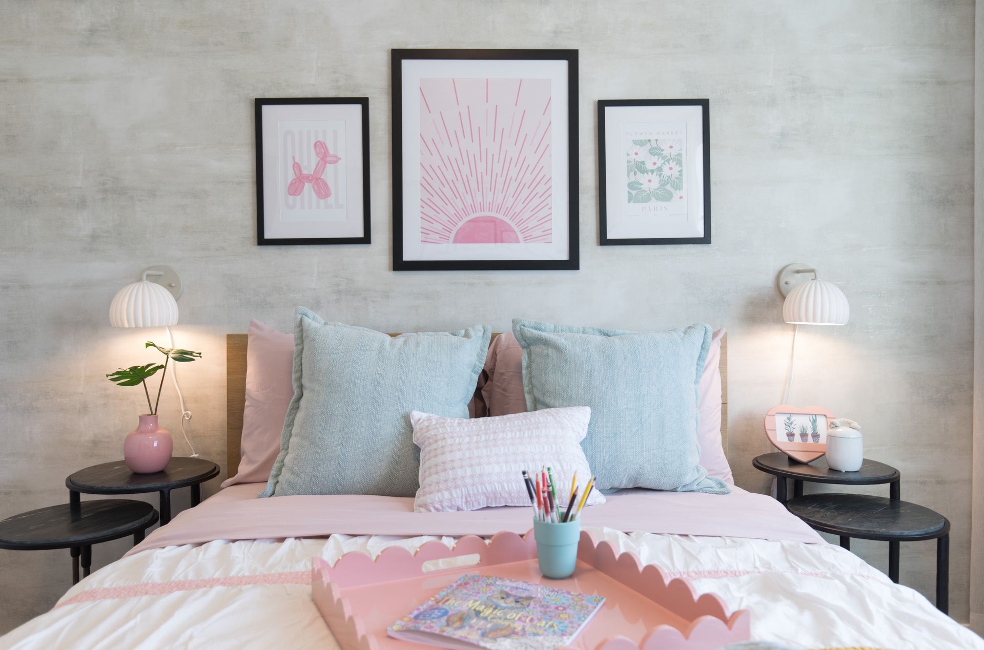 A bedroom with a bed , tables , lamps and a tray on the bed.