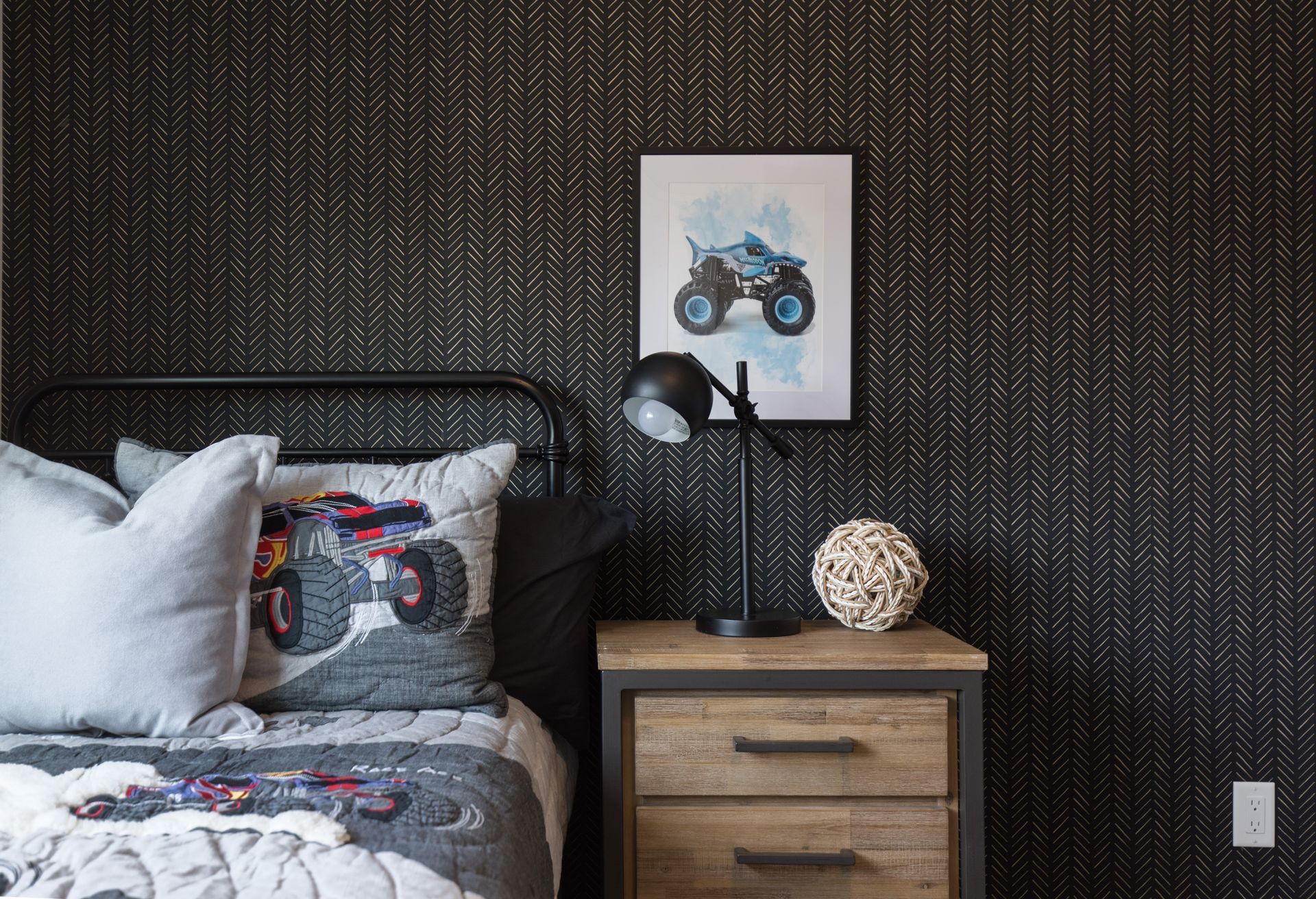 There is a picture of a monster truck on the wall above the bed.