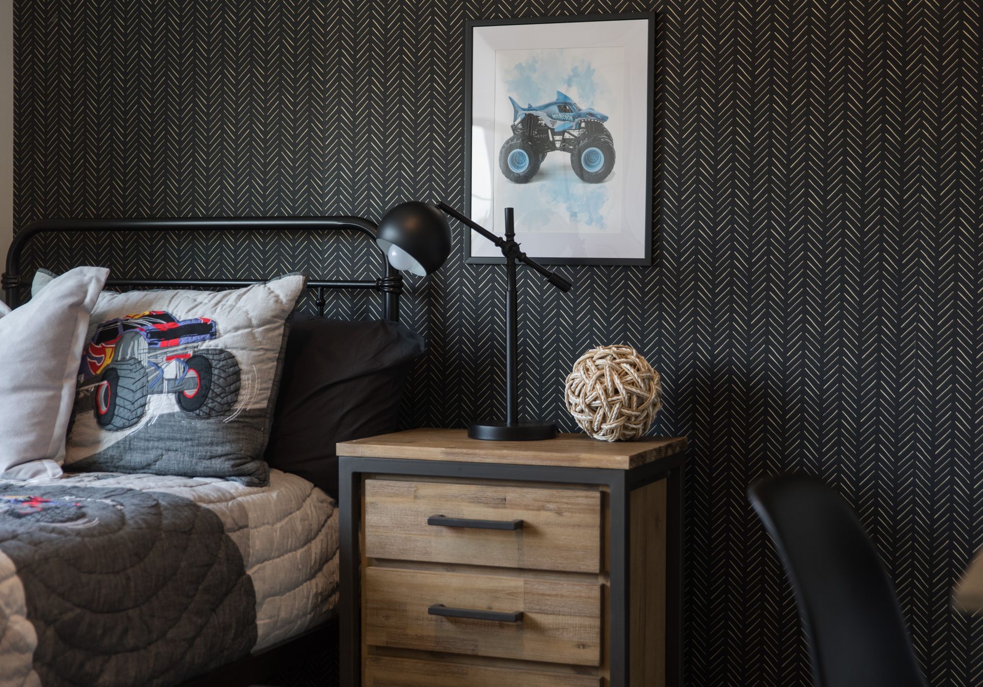 There is a picture of a monster truck on the wall above the bed.