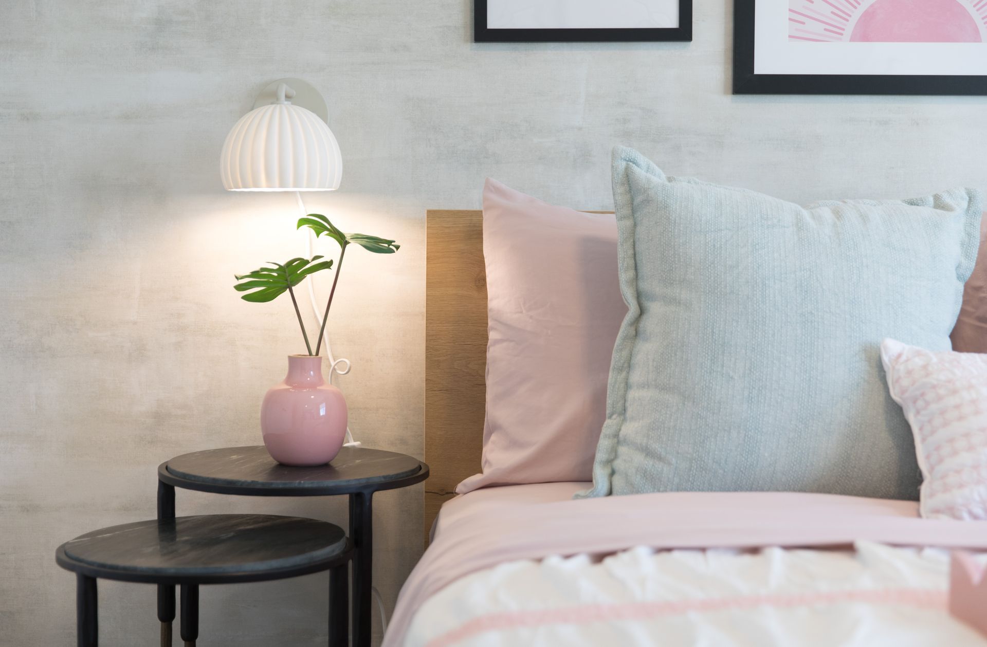 A bedroom with a bed , nightstand , lamp and pillows