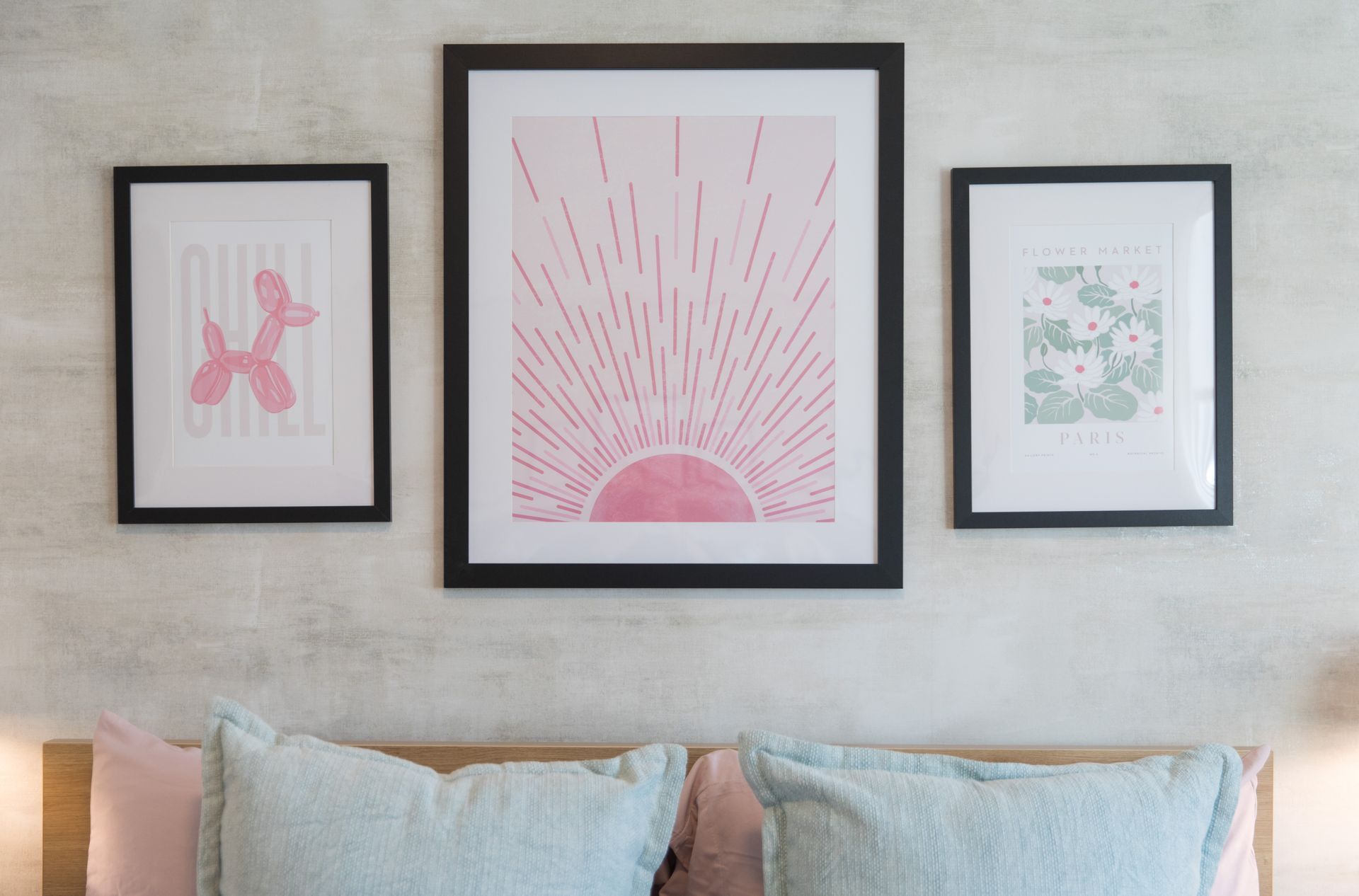 Three framed pictures are hanging on a wall above a bed.