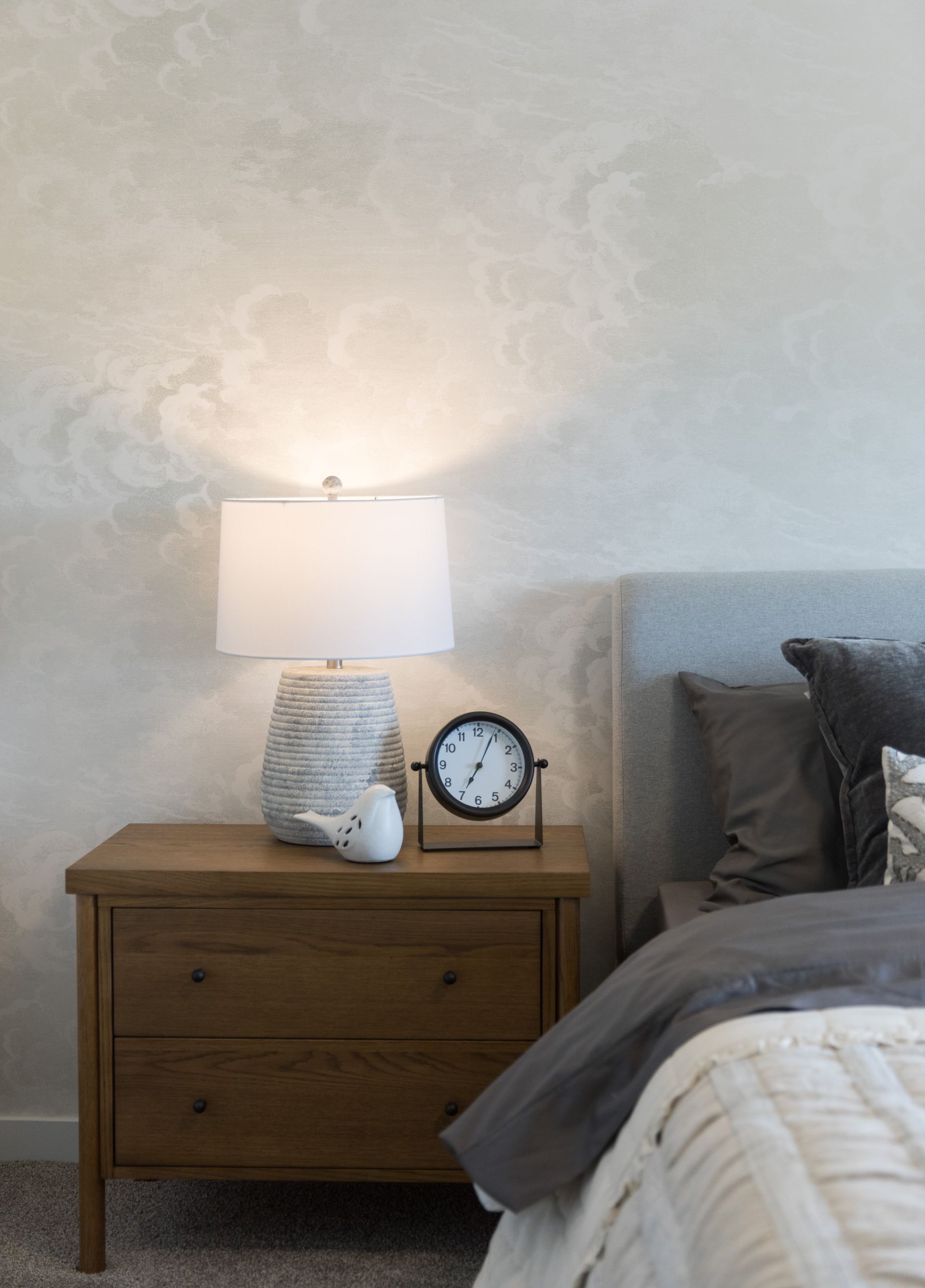 A bedroom with a bed , nightstand , lamp and clock