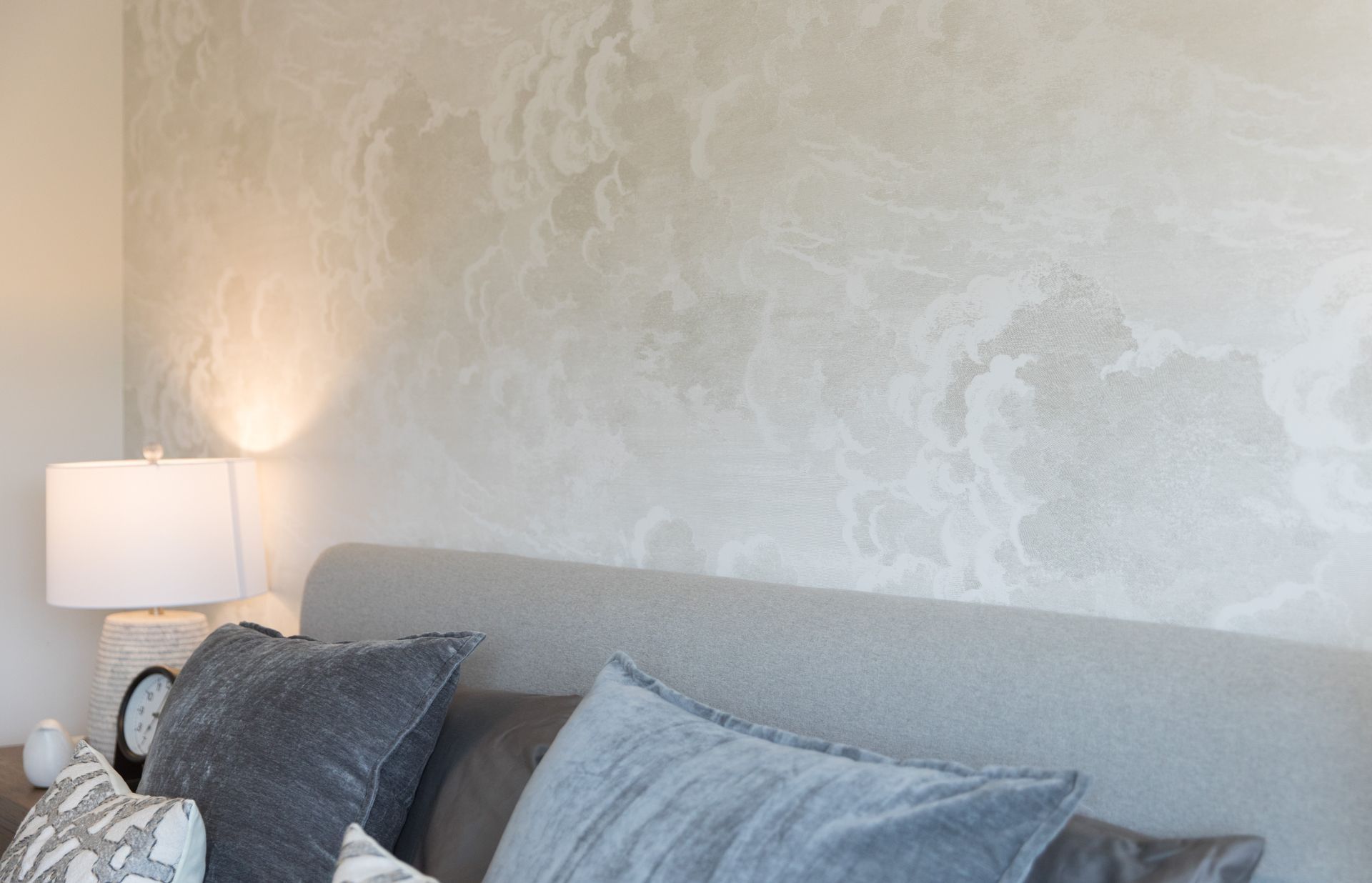 A bed with pillows and a lamp in a bedroom with a white wall.