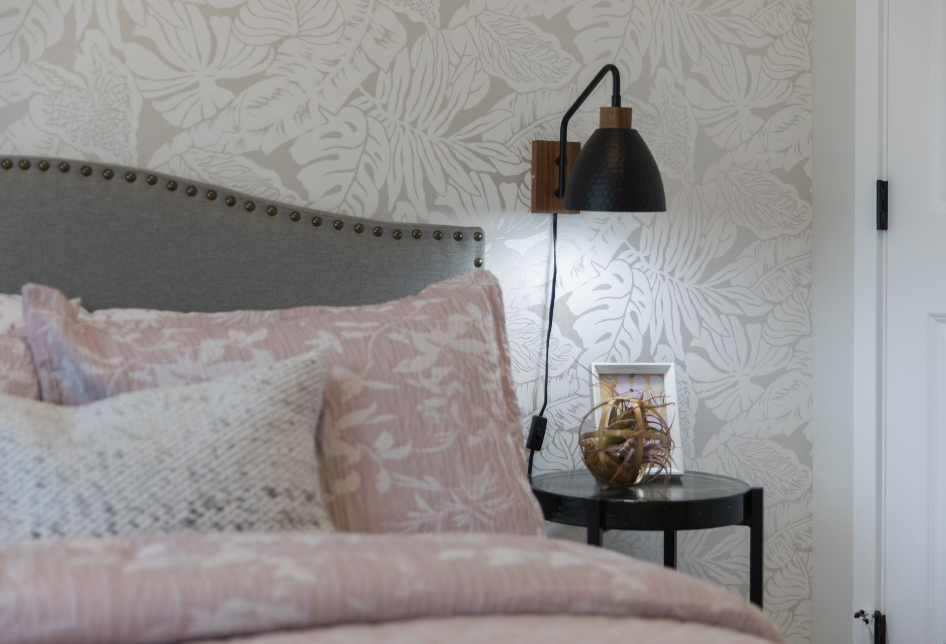 A bedroom with a bed , nightstand , and lamp.