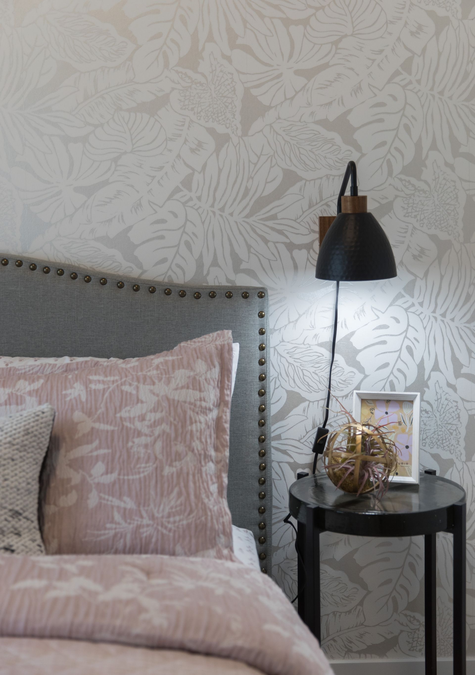 A bedroom with a bed , nightstand and lamp