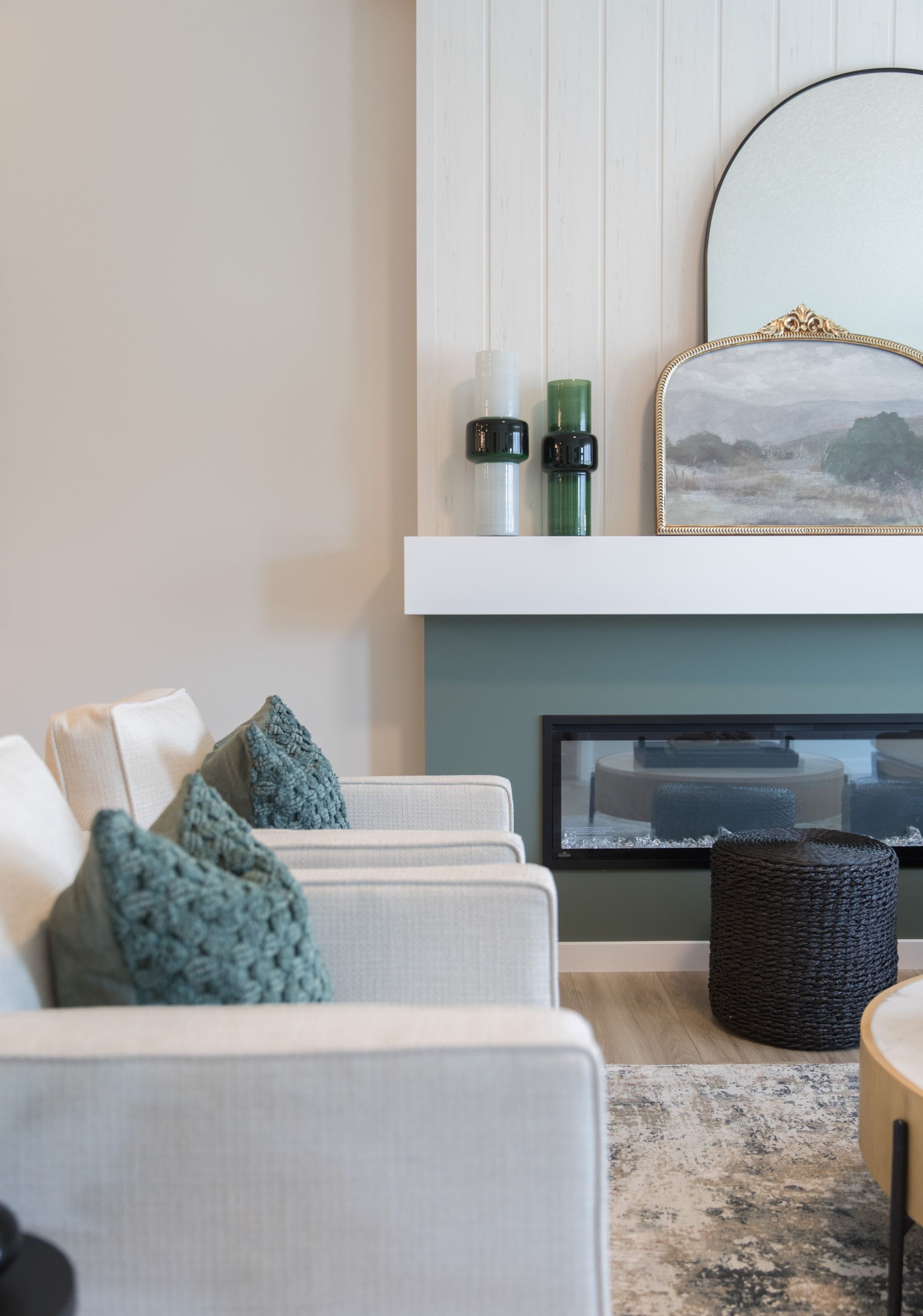 A living room with two chairs , a fireplace and a mirror.