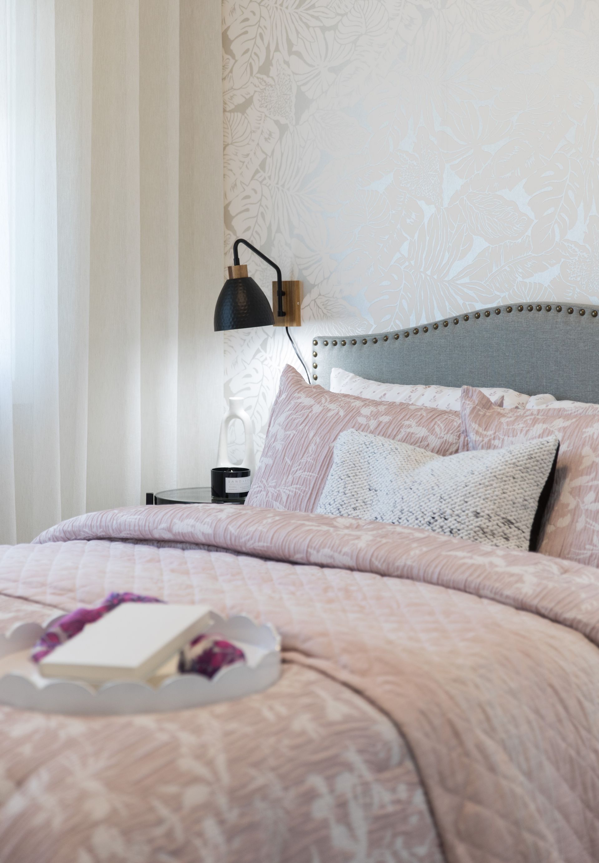 A bed with a pink comforter and pillows in a bedroom.