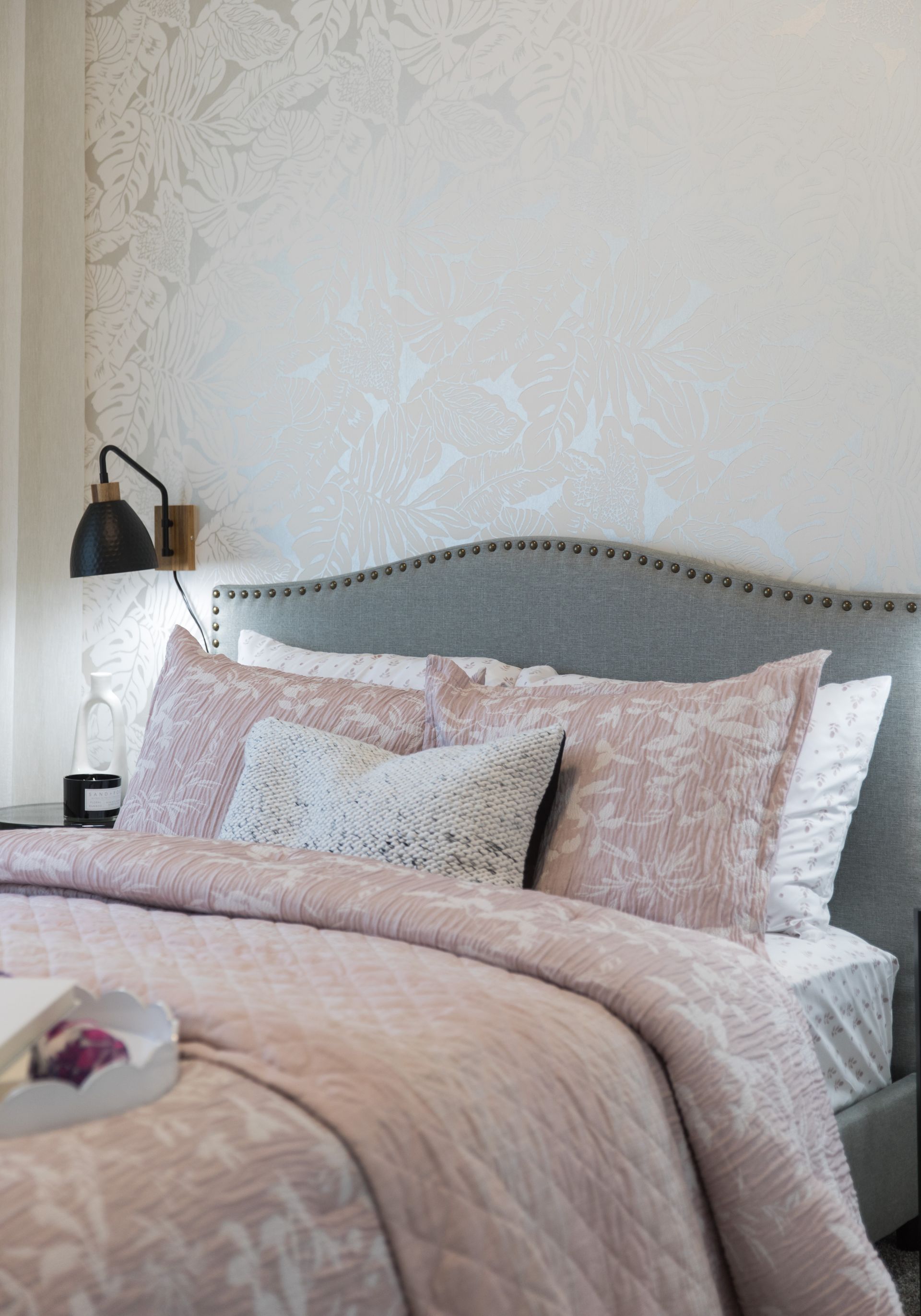 A bed with a pink comforter and pillows in a bedroom.