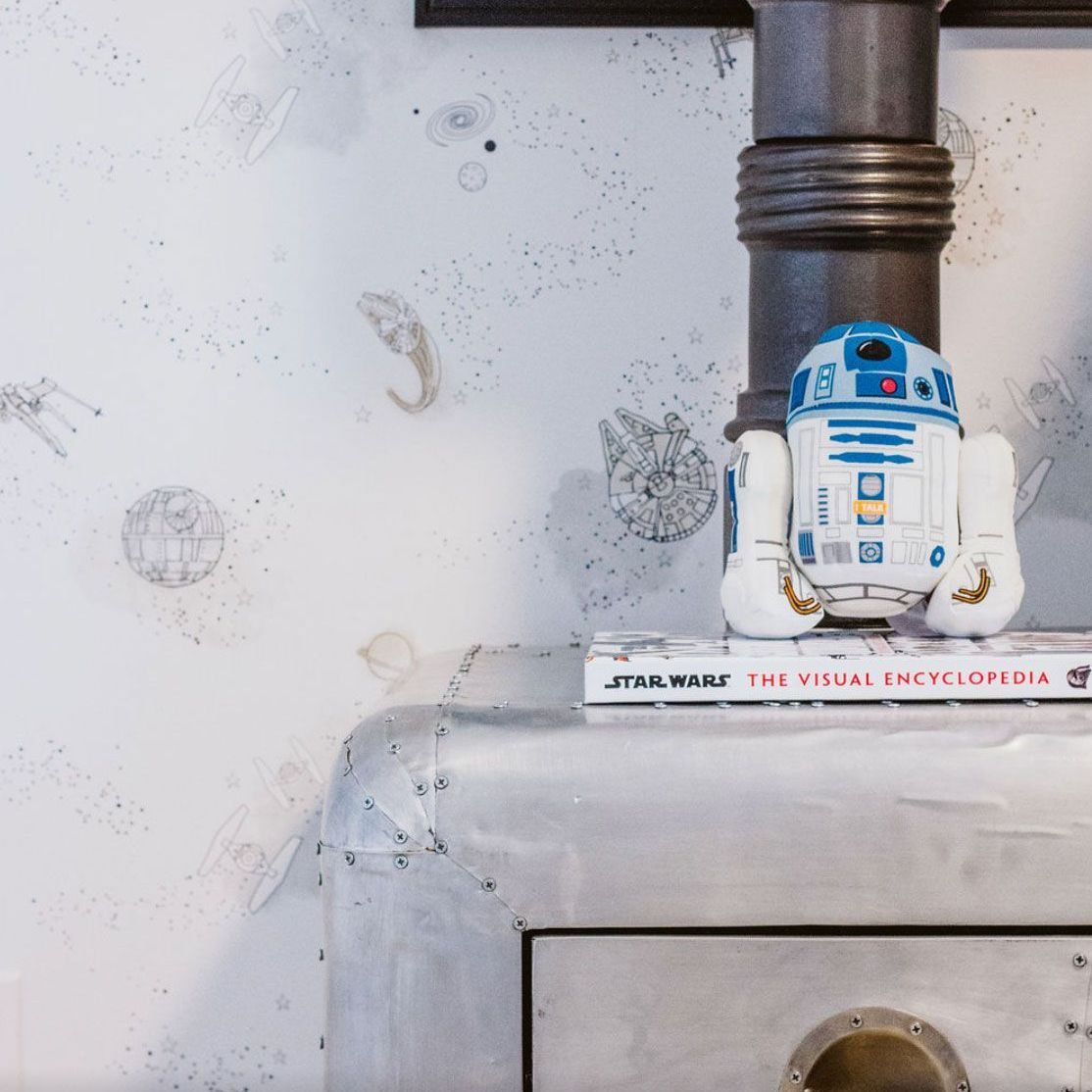 A r2d2 toy is sitting on top of a star wars book