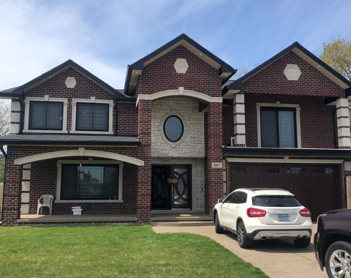 A large brick house with a car parked in front of it.