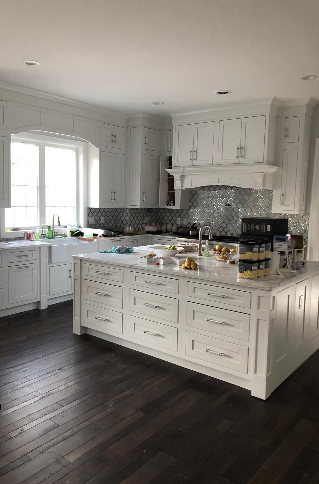 A kitchen with white cabinets and a large island in the middle.