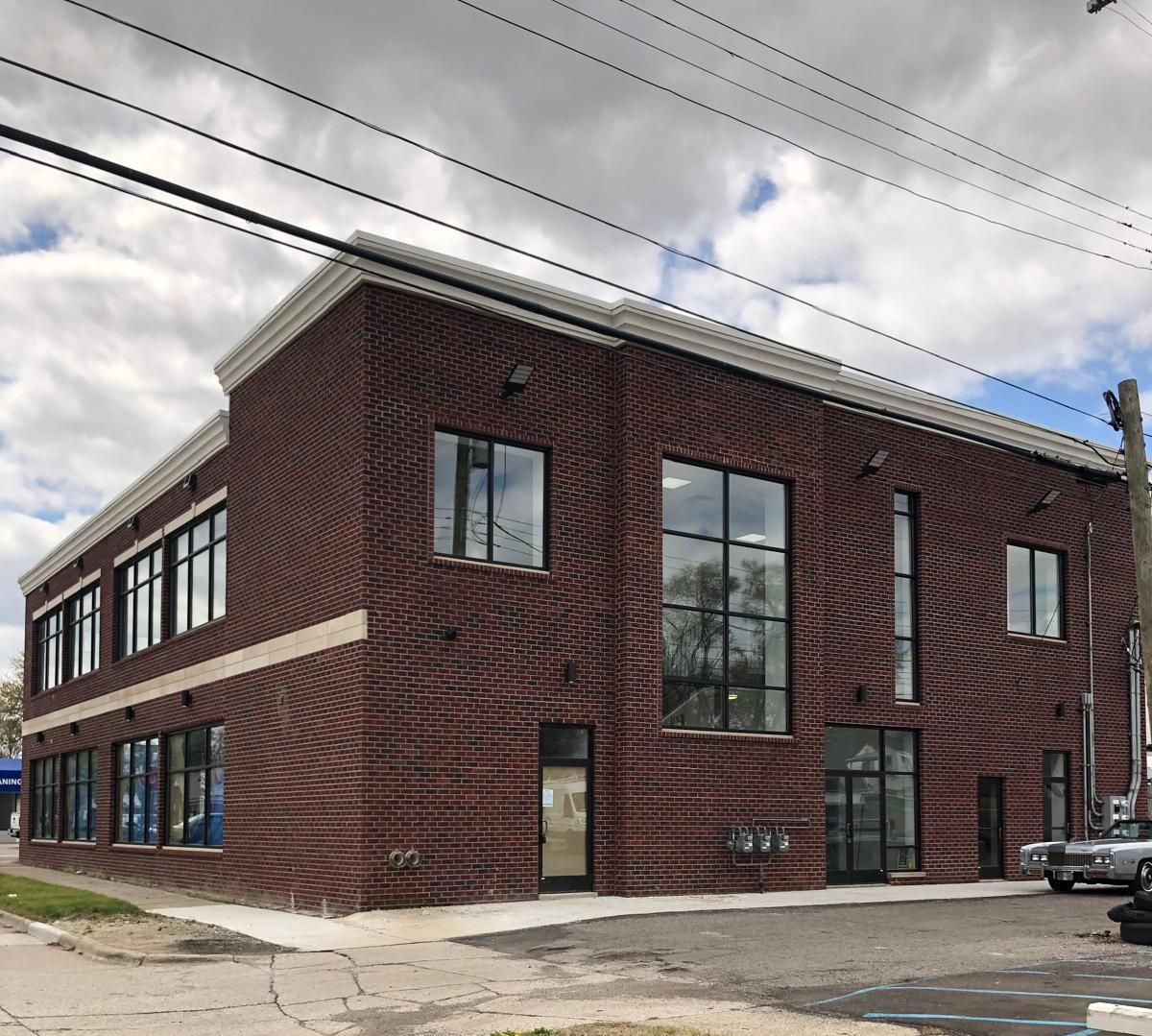 A large brick building with a lot of windows and a parking lot in front of it.