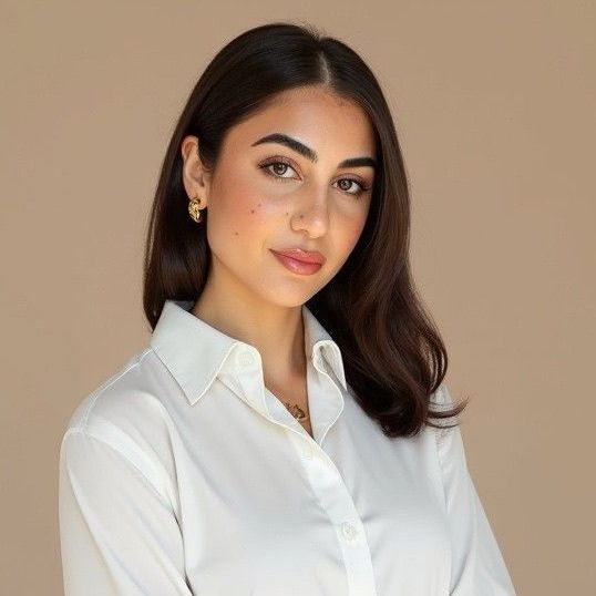 A woman with long dark hair is wearing a white shirt and smiling