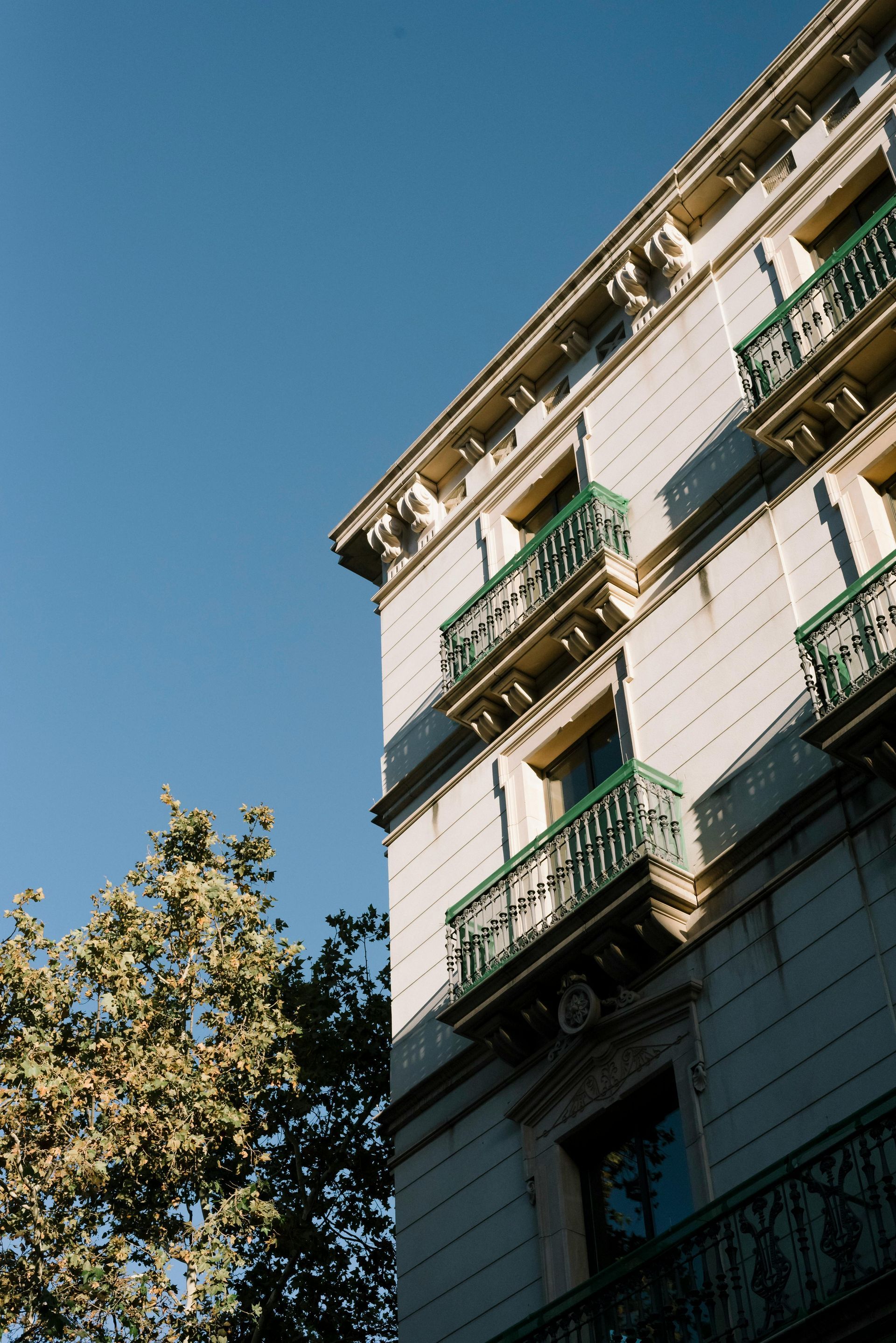 A white building with green balconies against a blue sky