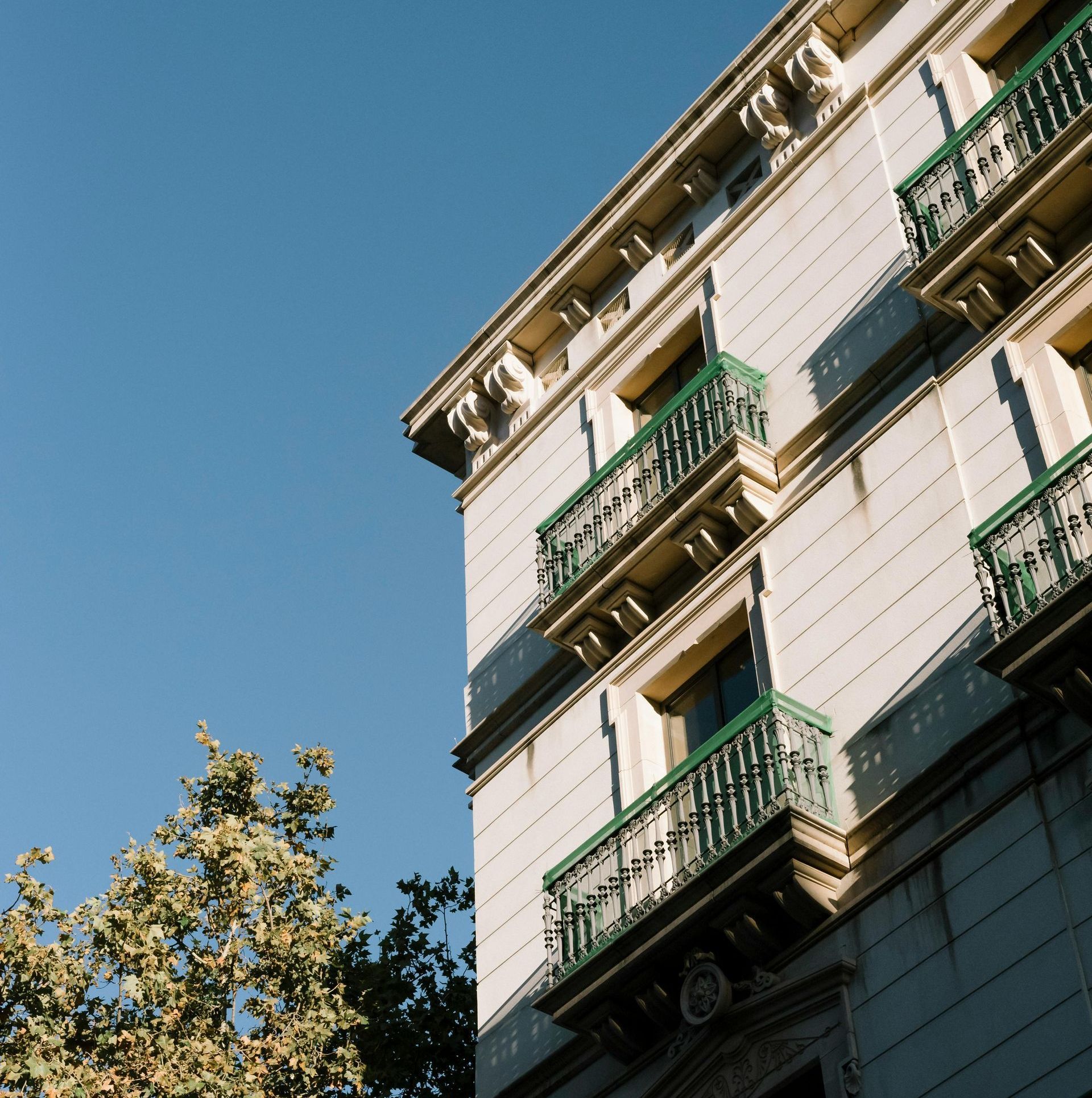 A white building with green balconies against a blue sky