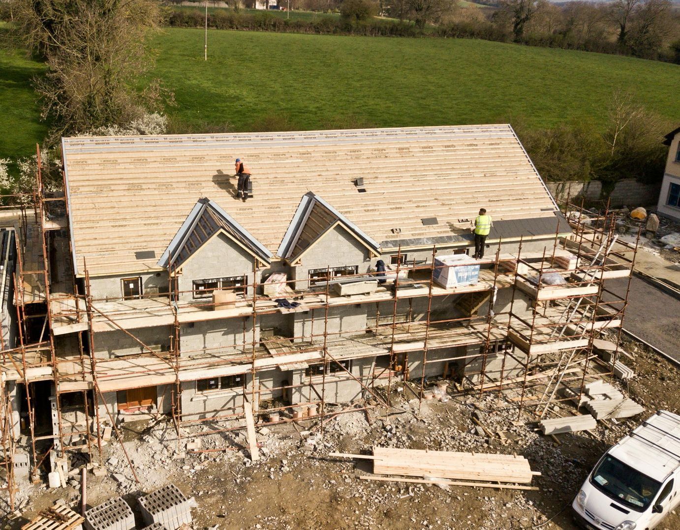 A white van is parked in front of a building under construction