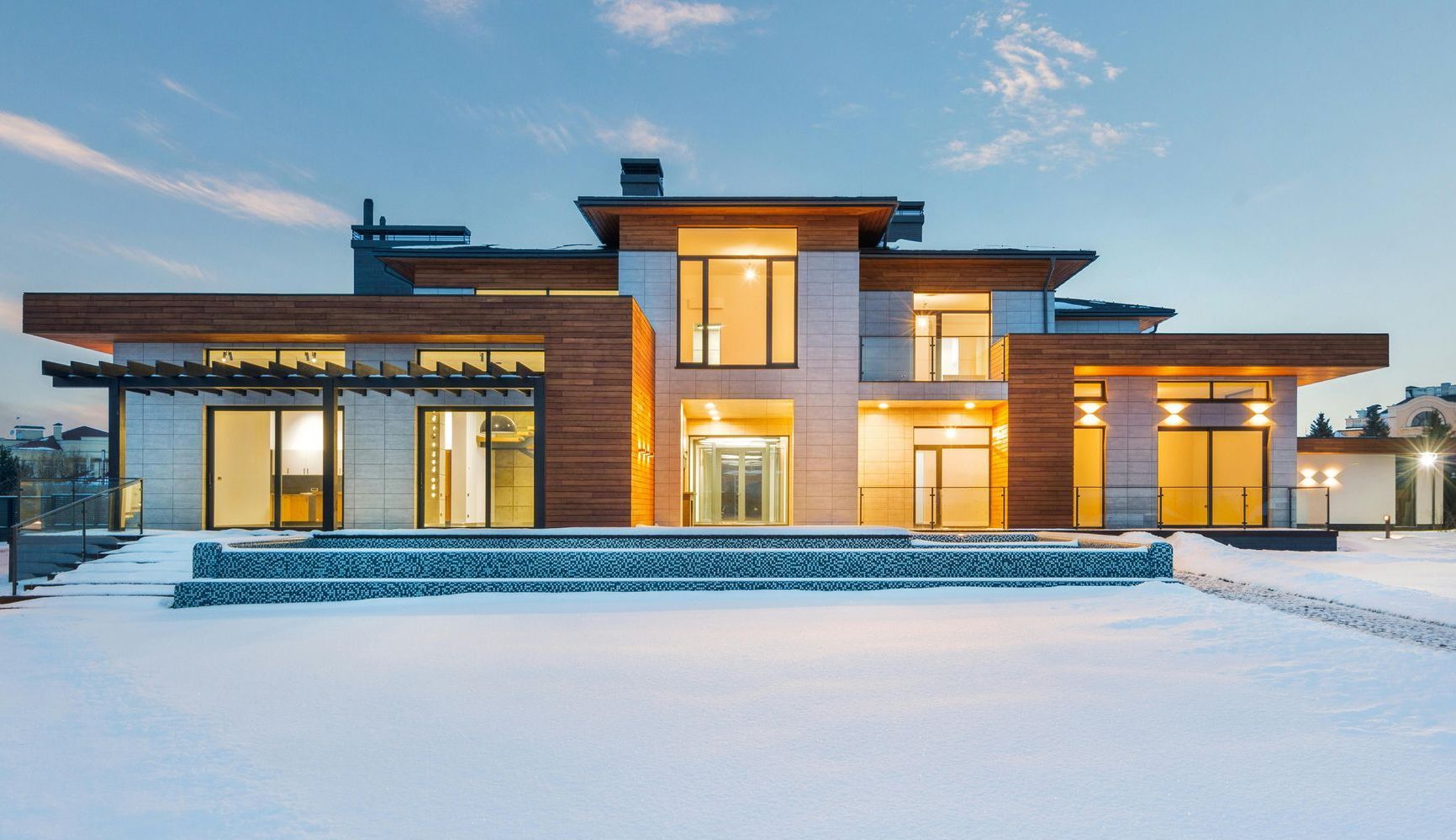A large house with a lot of windows is sitting on top of a snow covered field.