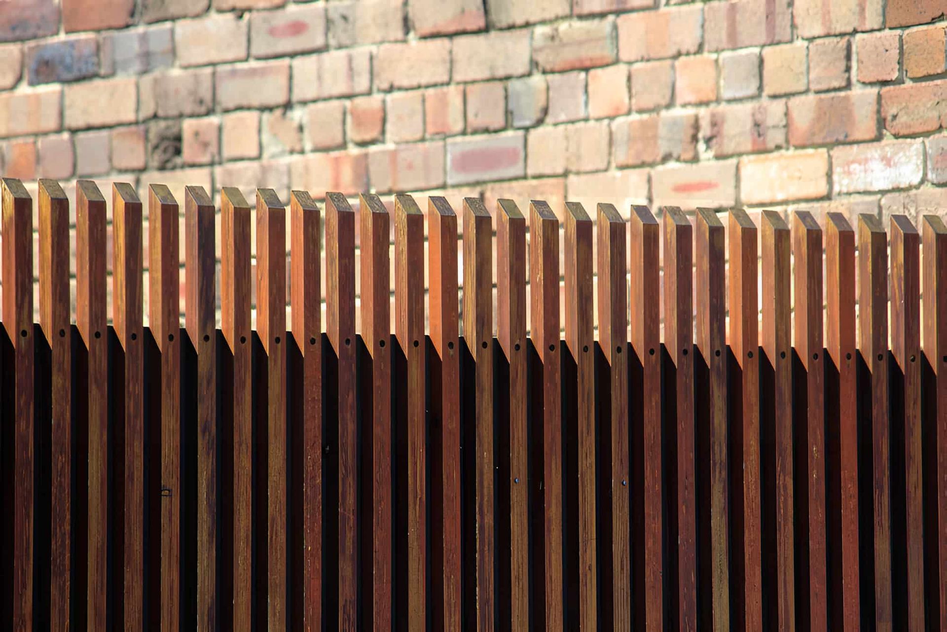 A Wooden Fence in Front of a Brick Wall — Pride Carpentry & Maintenance In Berkeley Vale, NSW