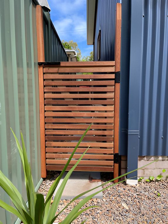 A Wooden Gate is Located Next to a House — Pride Carpentry & Maintenance In Berkeley Vale, NSW